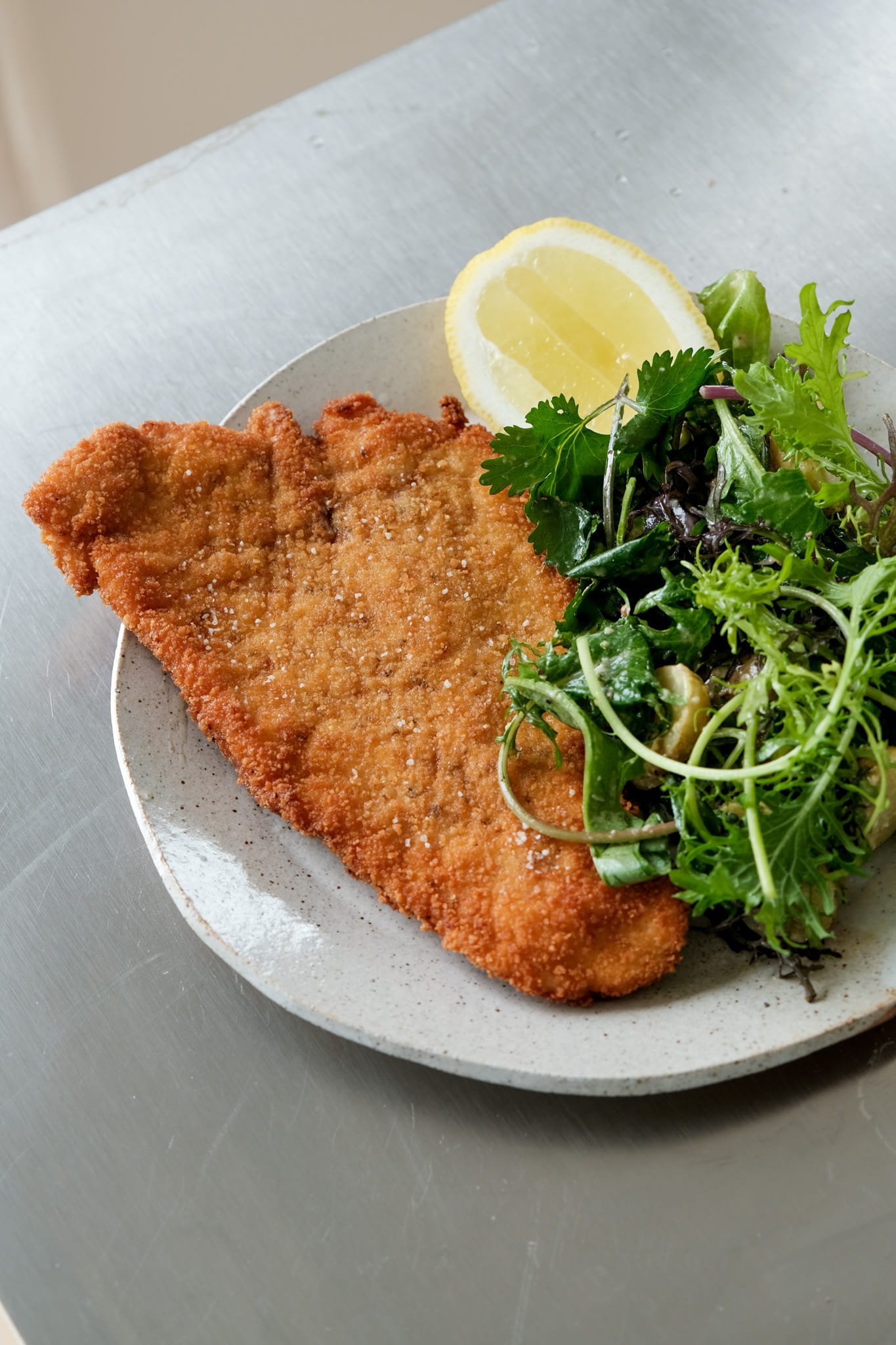 Assiette gourmande d'été : Schnitzel extra-croustillant accompagné de sa salade de grenailles façon César et d'un quartier de citron.