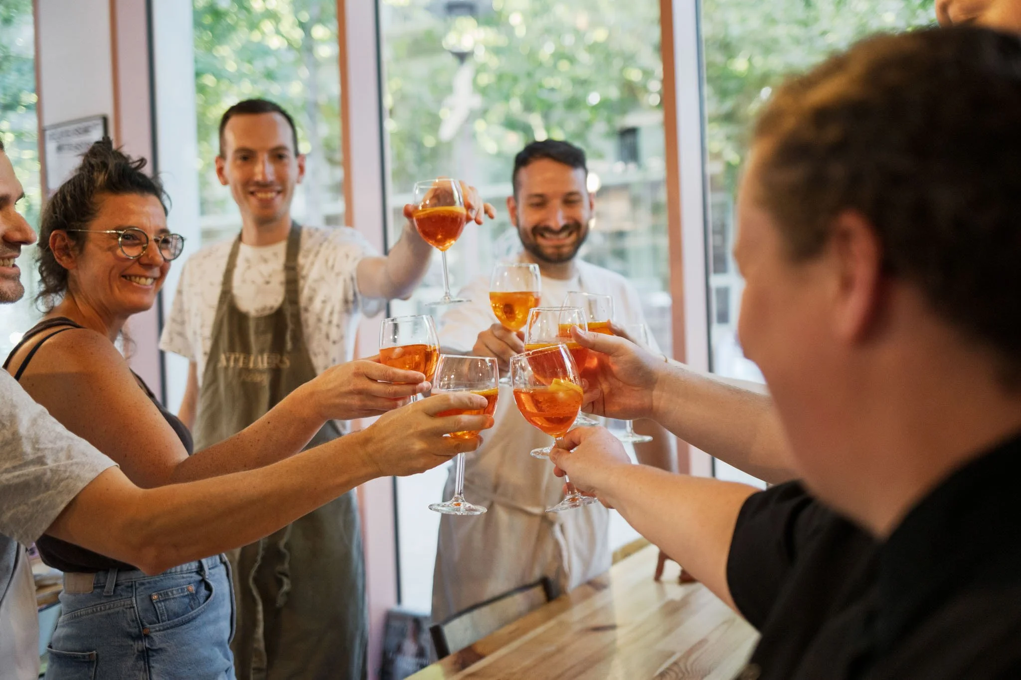 Les participants d'un cours de cuisine team building trinquent ensemble chaleureusement avec un verre de bienvenue.