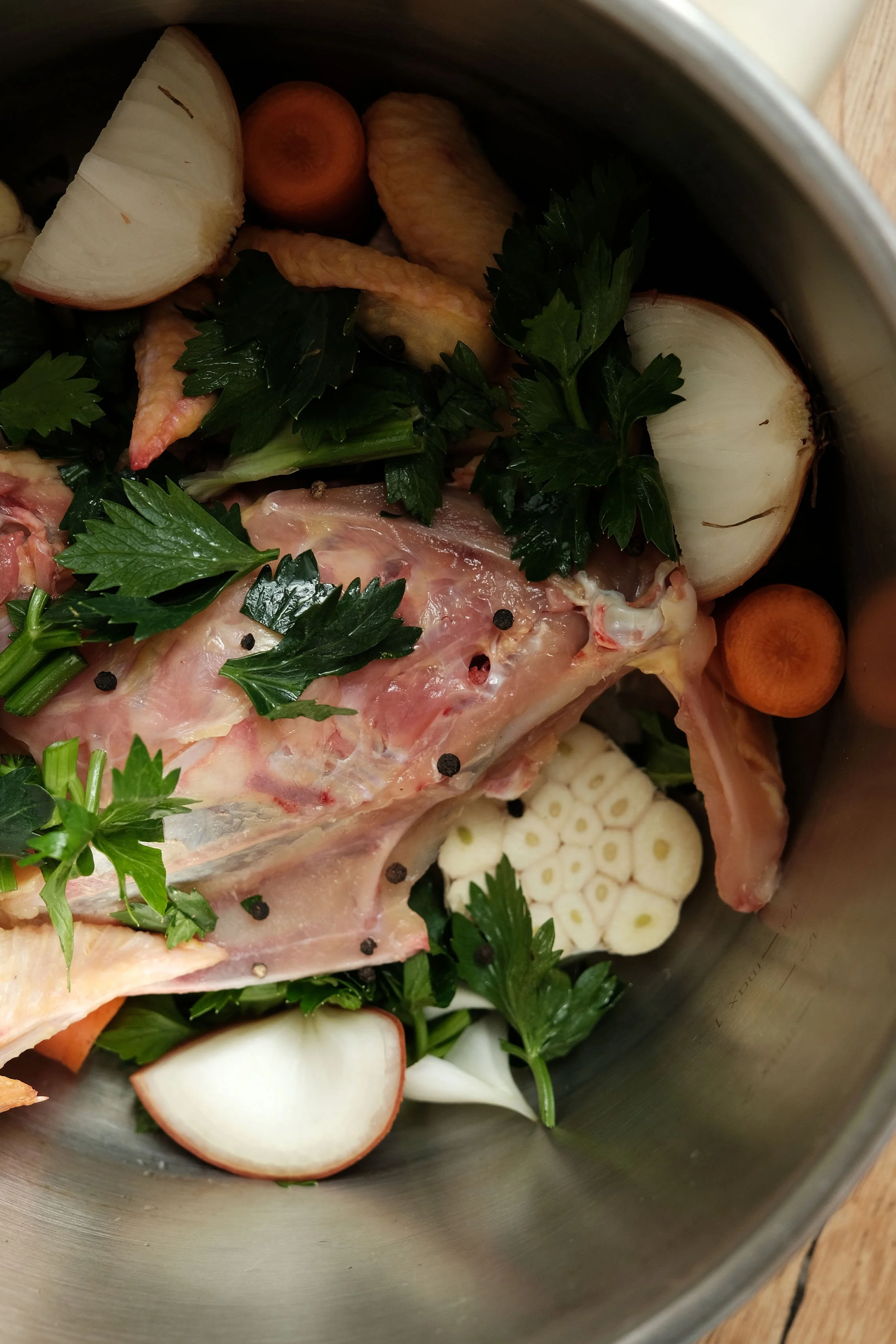 Ingrédients pour réaliser un bouillon de poulet : carcasse de poulet, carottes, persil, oignons, ail