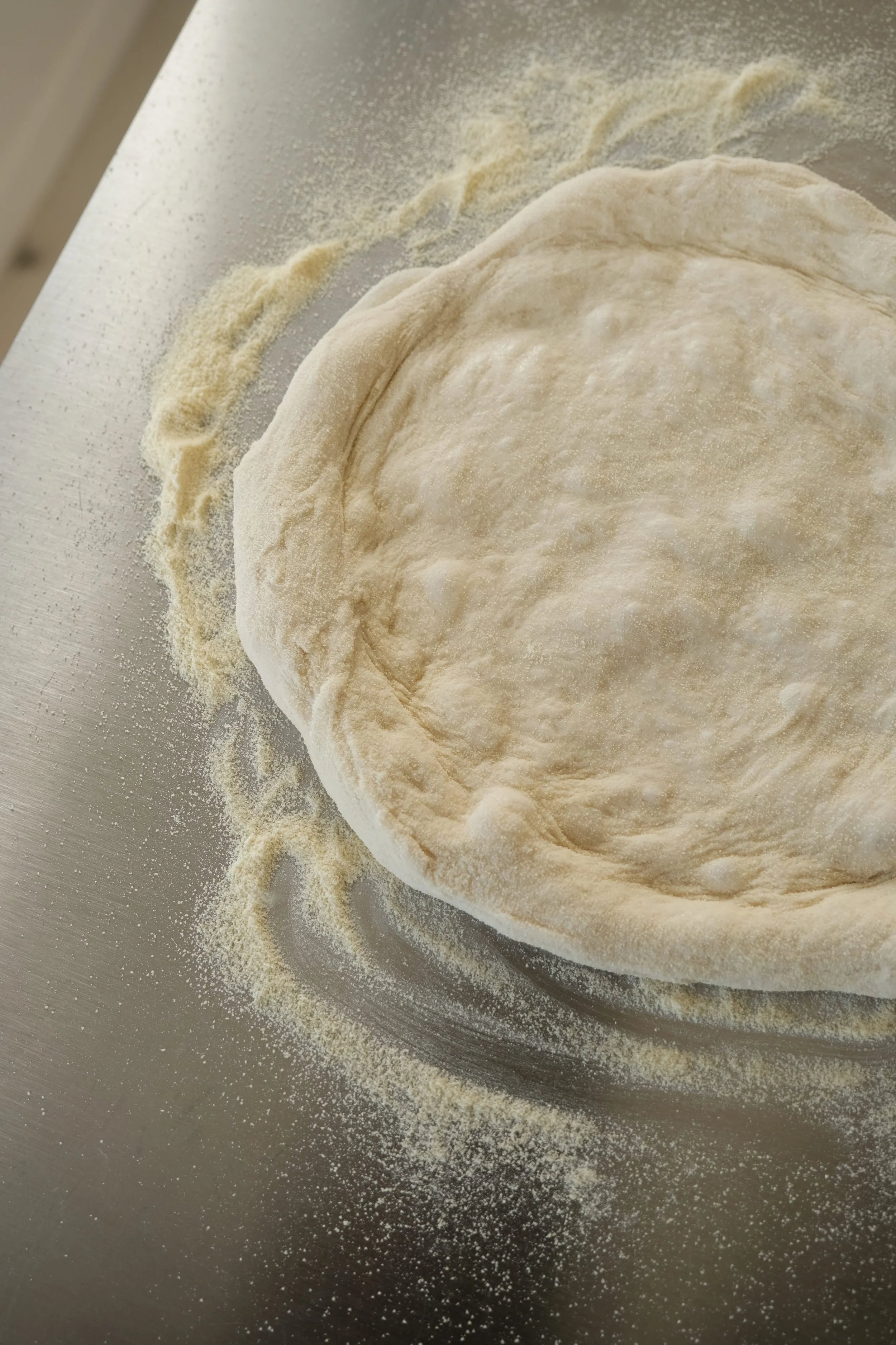 Façonnage et étalage manuel d'une pâte à pizza napolitaine en cours de cuisine à Nantes.
