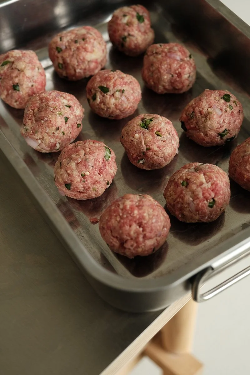 Préparation de polpette maison crues aux herbes fraîches disposées sur un plat en inox, recette cuisine italienne