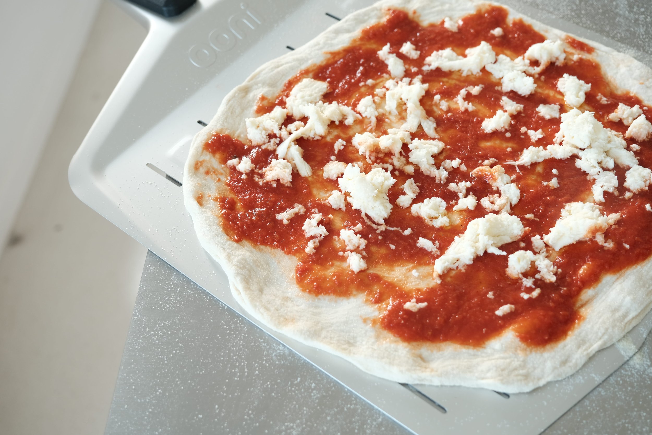 Pizza garnie sur une pelle prête à être enfournée pendant le cours de pizza à Nantes.