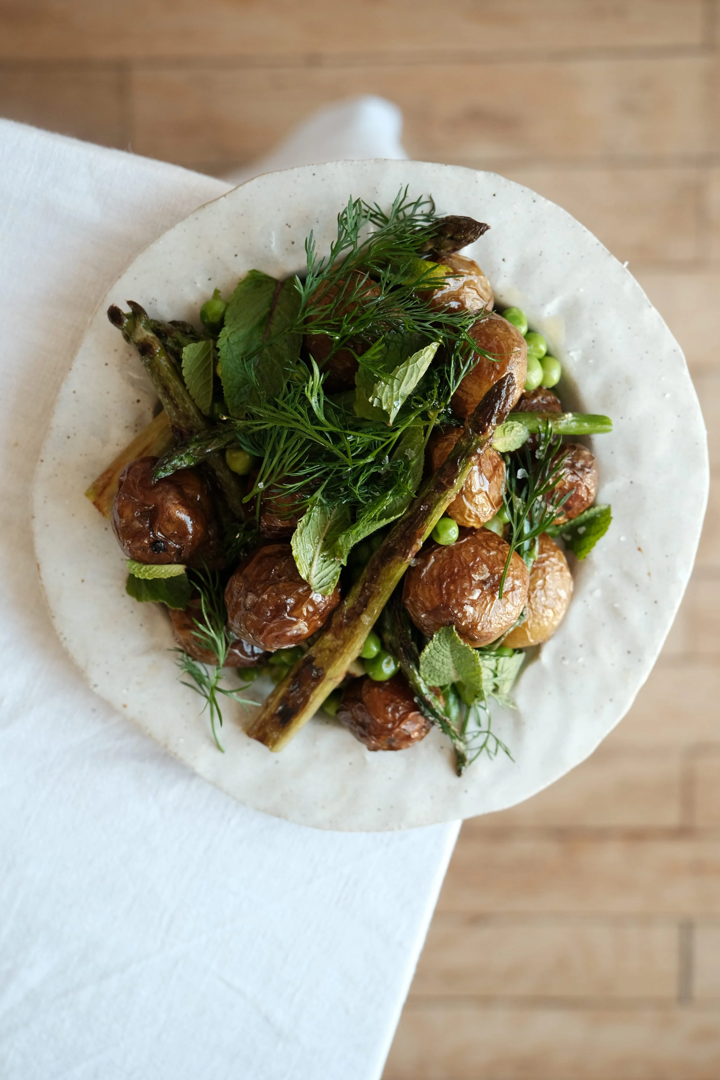 Assiette de légumes primeurs printaniers vue de haut : pommes de terre fondantes, asperges vertes et petits pois.
