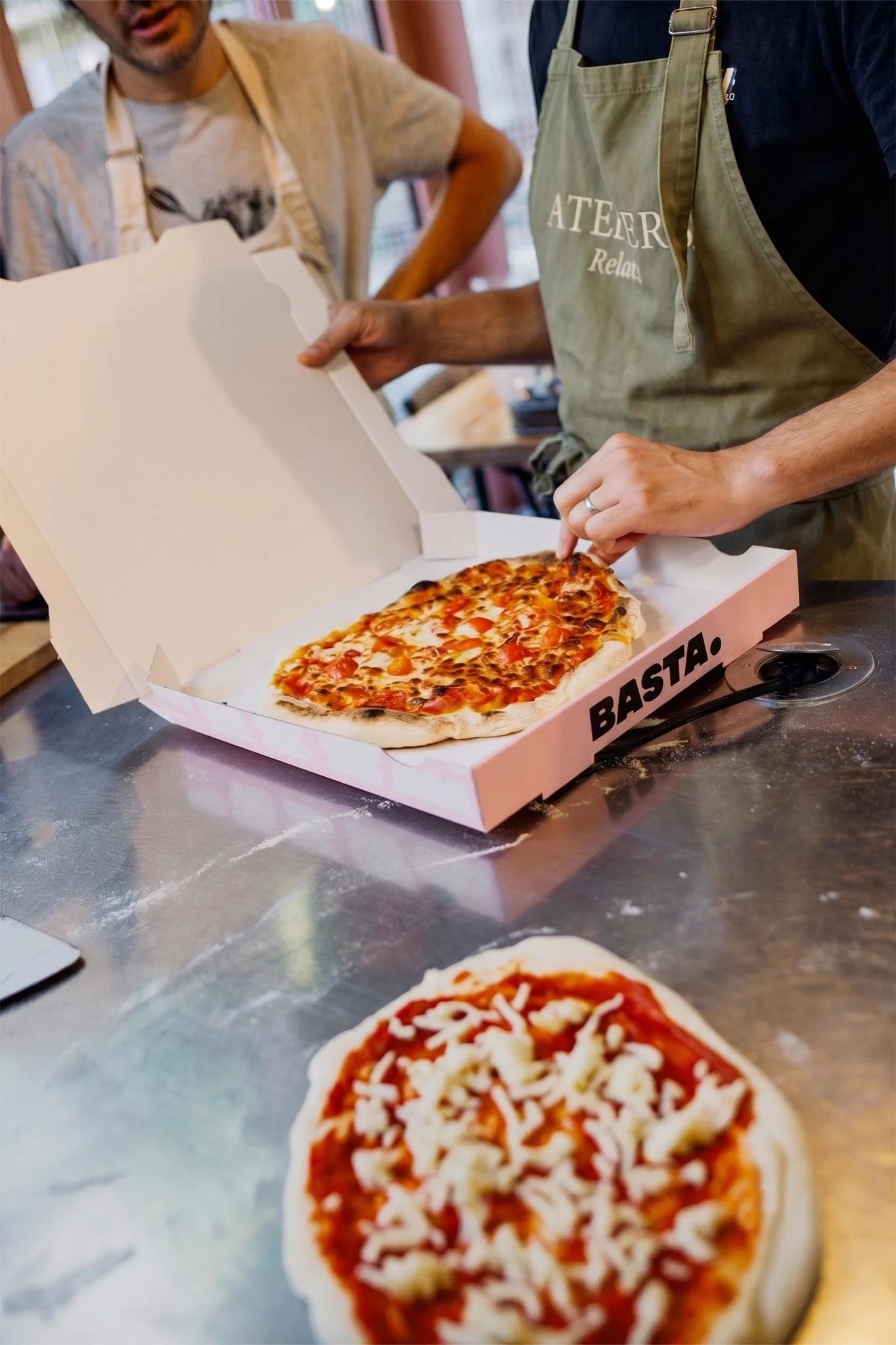 Une pizza napolitaine alvéolée et bien garnie présentée dans sa boîte à emporter signée BASTA.
