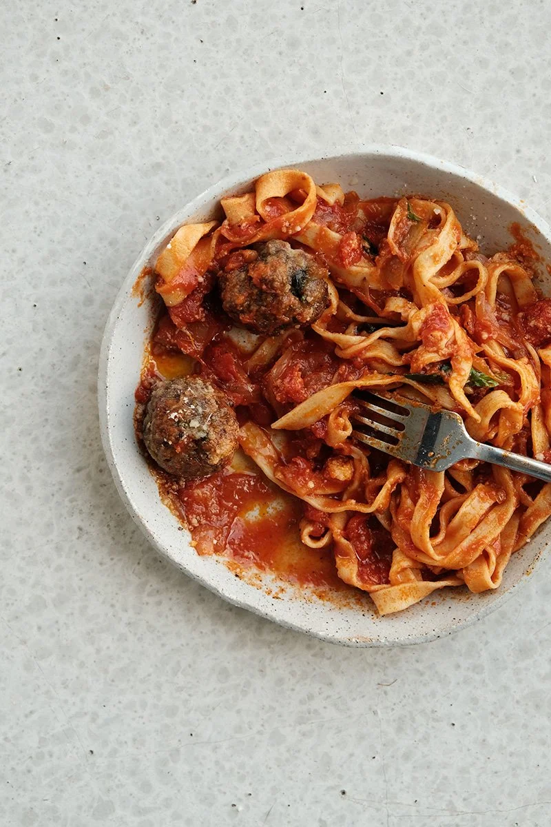 Assiette généreuse de polpette italiennes mijotées en sauce tomate, servies avec des tagliatelles fraîches maison dans un bol en céramique grè