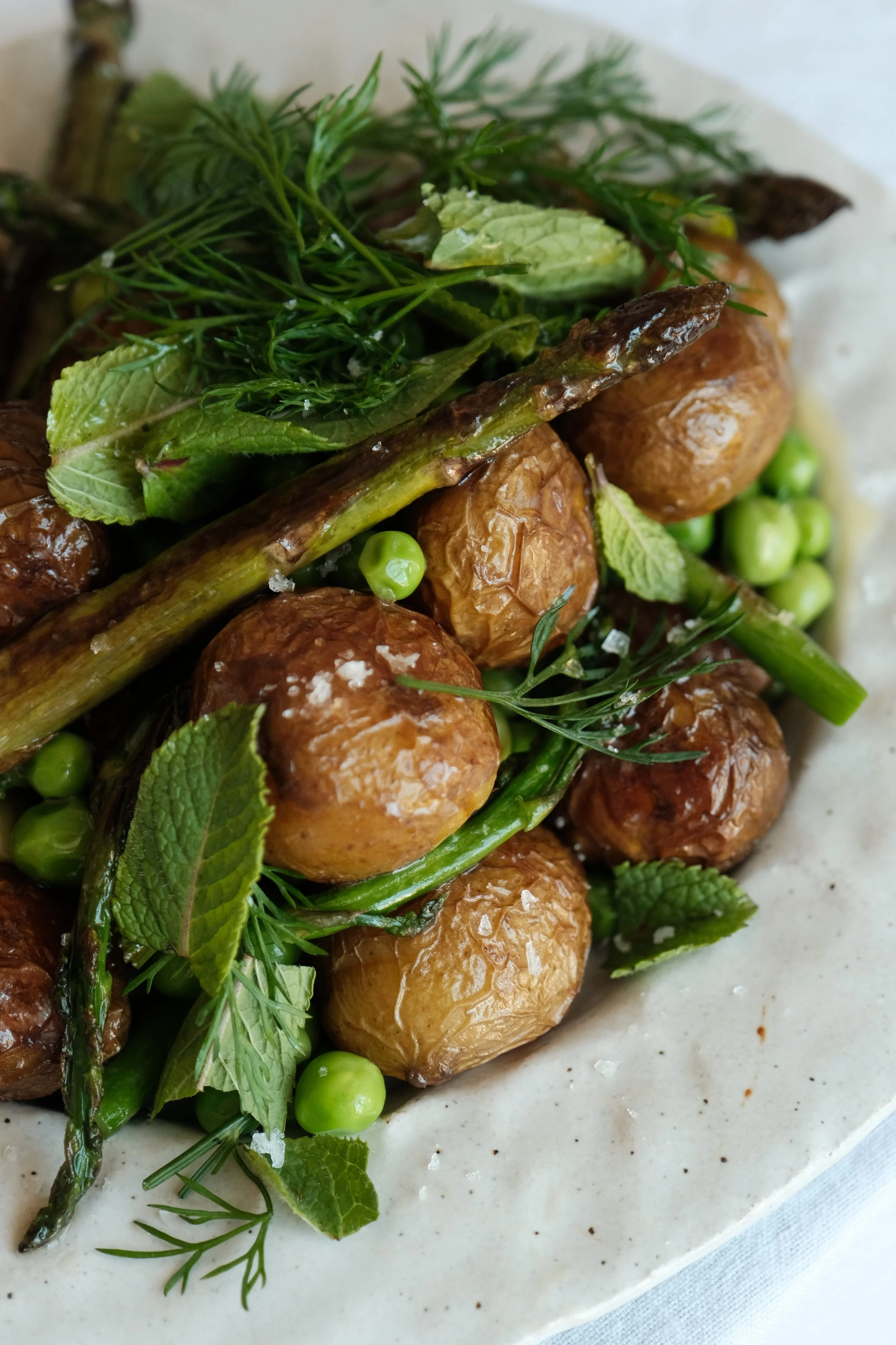 Gros plan sur des légumes de printemps croquants, sublimés par de la fleur de sel et des herbes fraîches.