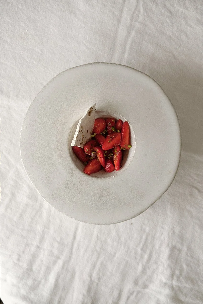 Dressage d'un dessert aux fraises fraîches et meringue croquante pendant un team building d'entreprise de pâtisserie à Paris.