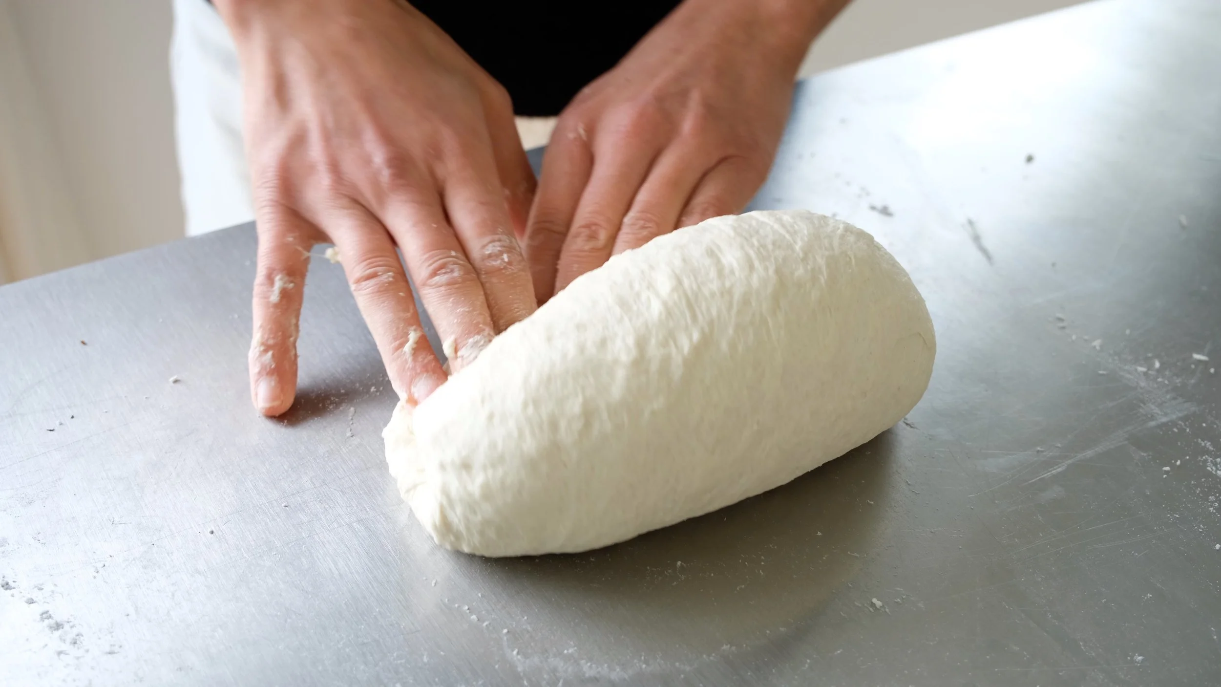 Mains pétrissant la pâte à pizza napolitaine lors d'un atelier de cuisine aux Ateliers Relief à Nantes.
