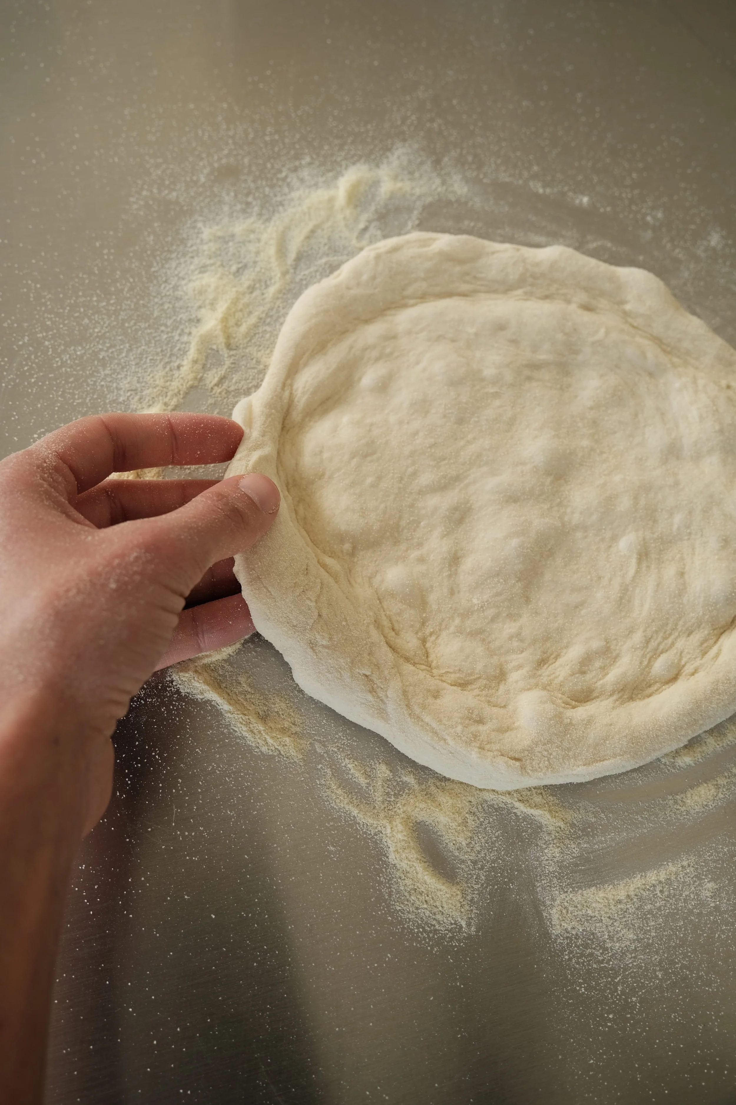 Pâte à pizza napolitaine étalée à la main lors d'un cours de cuisine aux Ateliers Relief à Nantes.