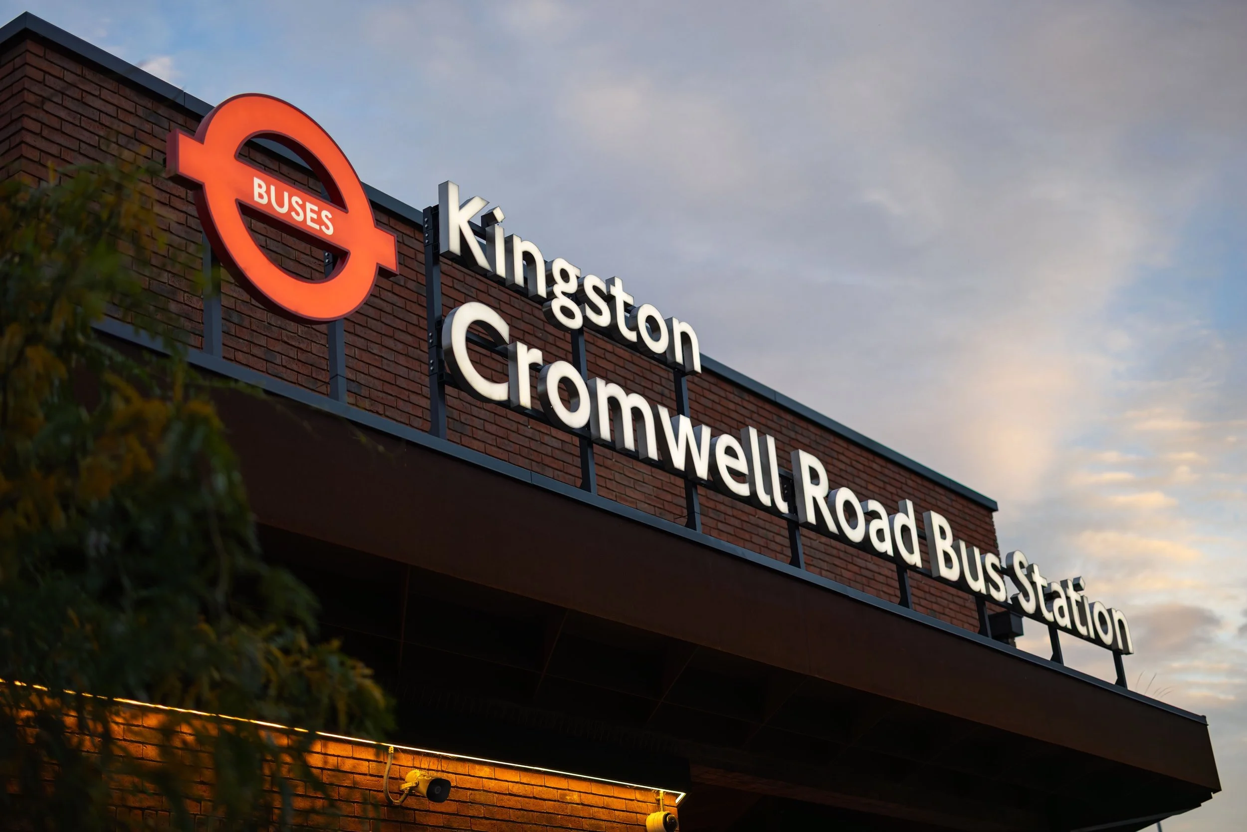 Sign for Kingston Cromwell Road Bus Station with the Transport for London logo, against a partly cloudy sky.