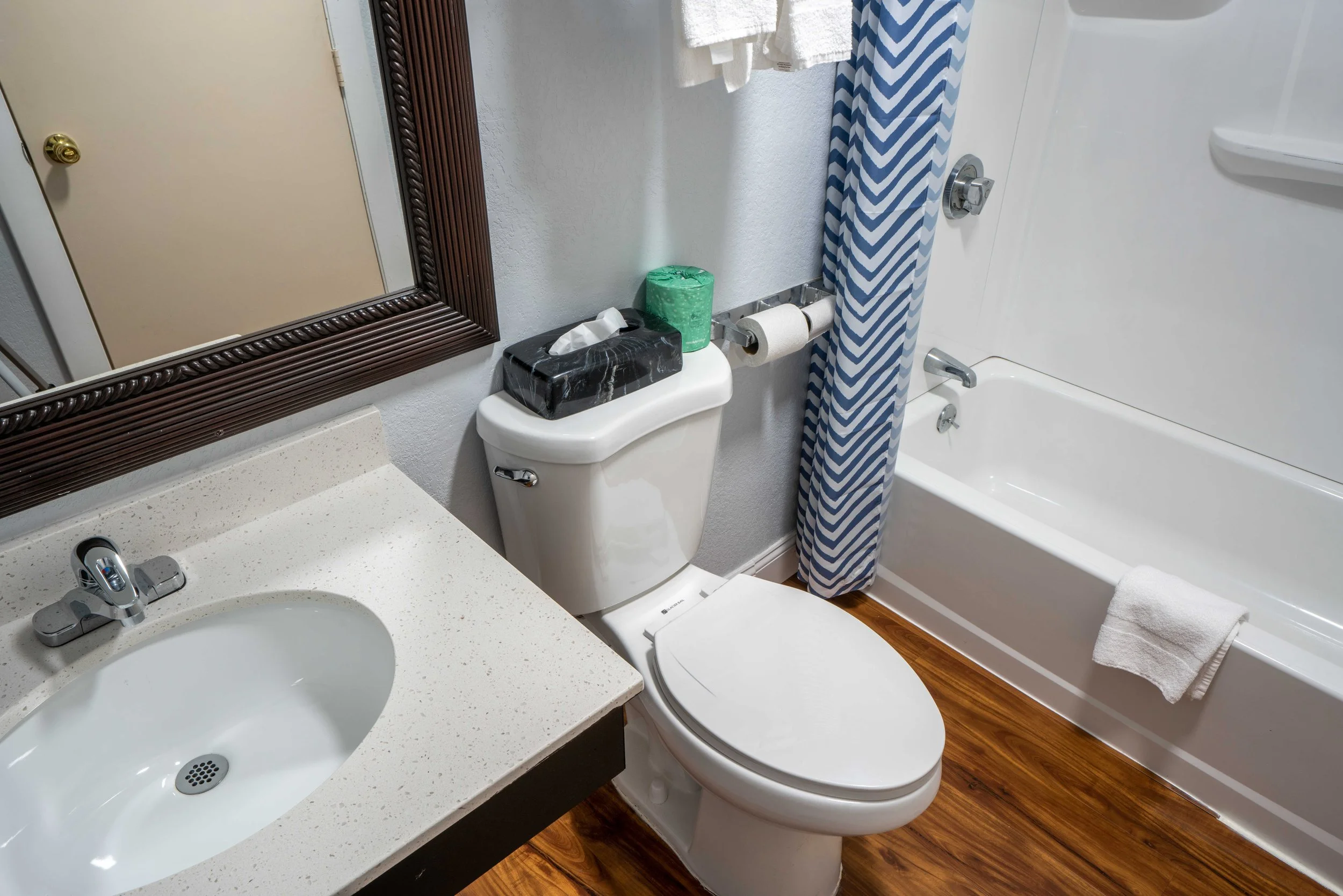 Modern bathroom with sink, toilet, mirror, bathtub, and blue chevron shower curtain.