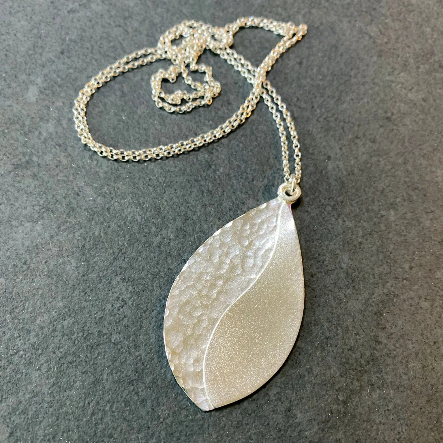 Teardrop shaped textured silver necklace on a chain