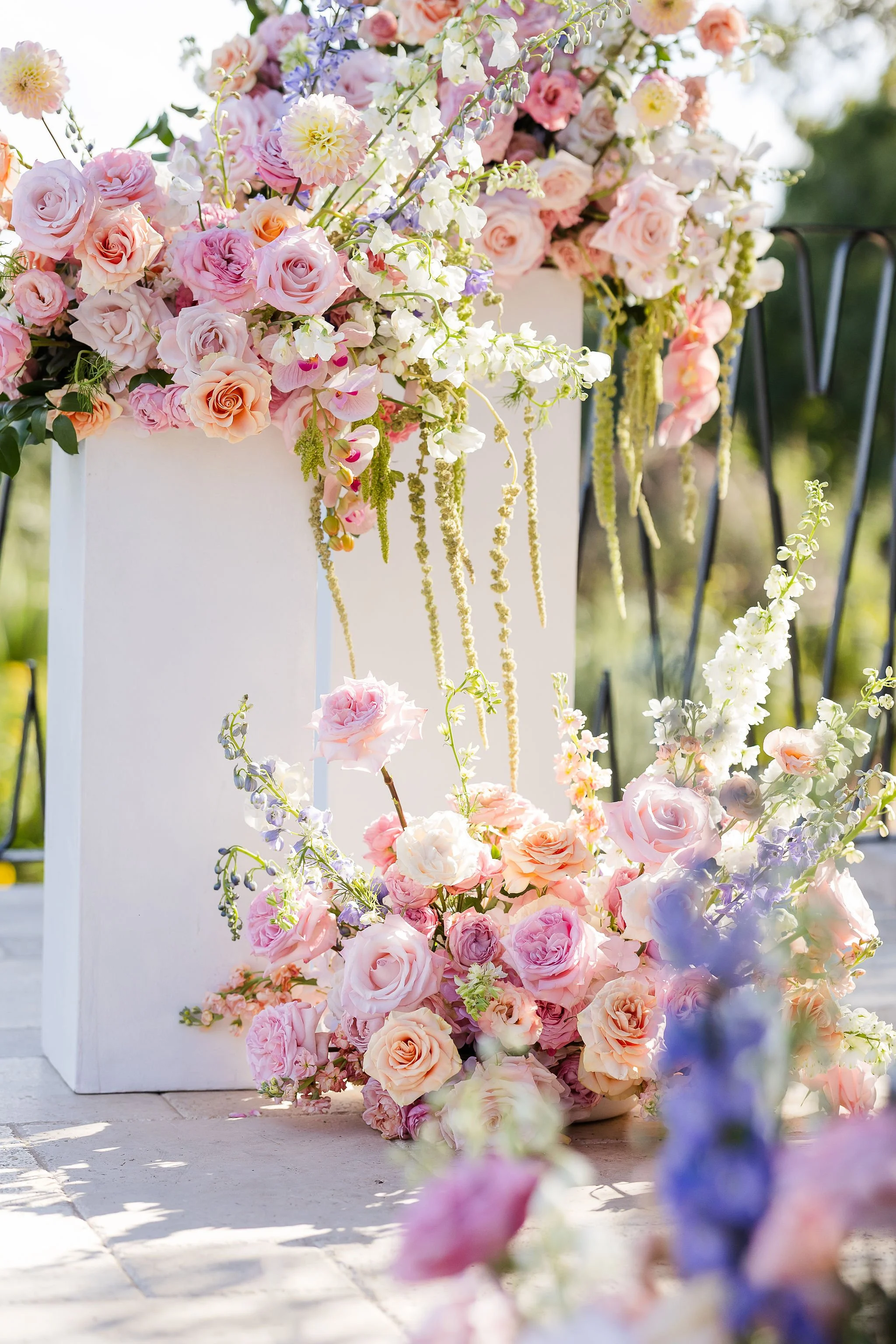 Lush ceremony florals on top of white pillars at the altar. 