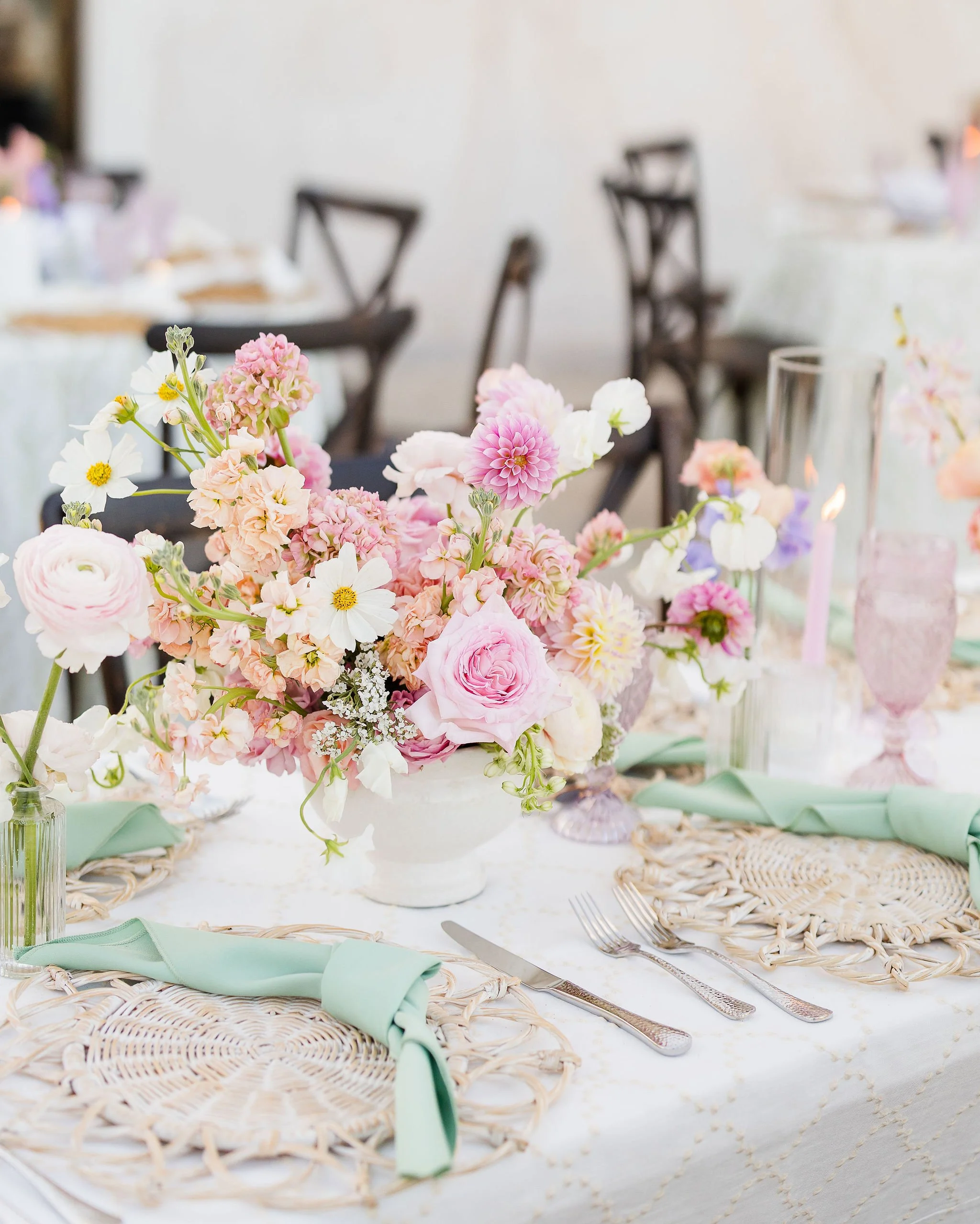  A gorgeous pastel wedding centerpiece on top of a table at an outdoor wedding. 