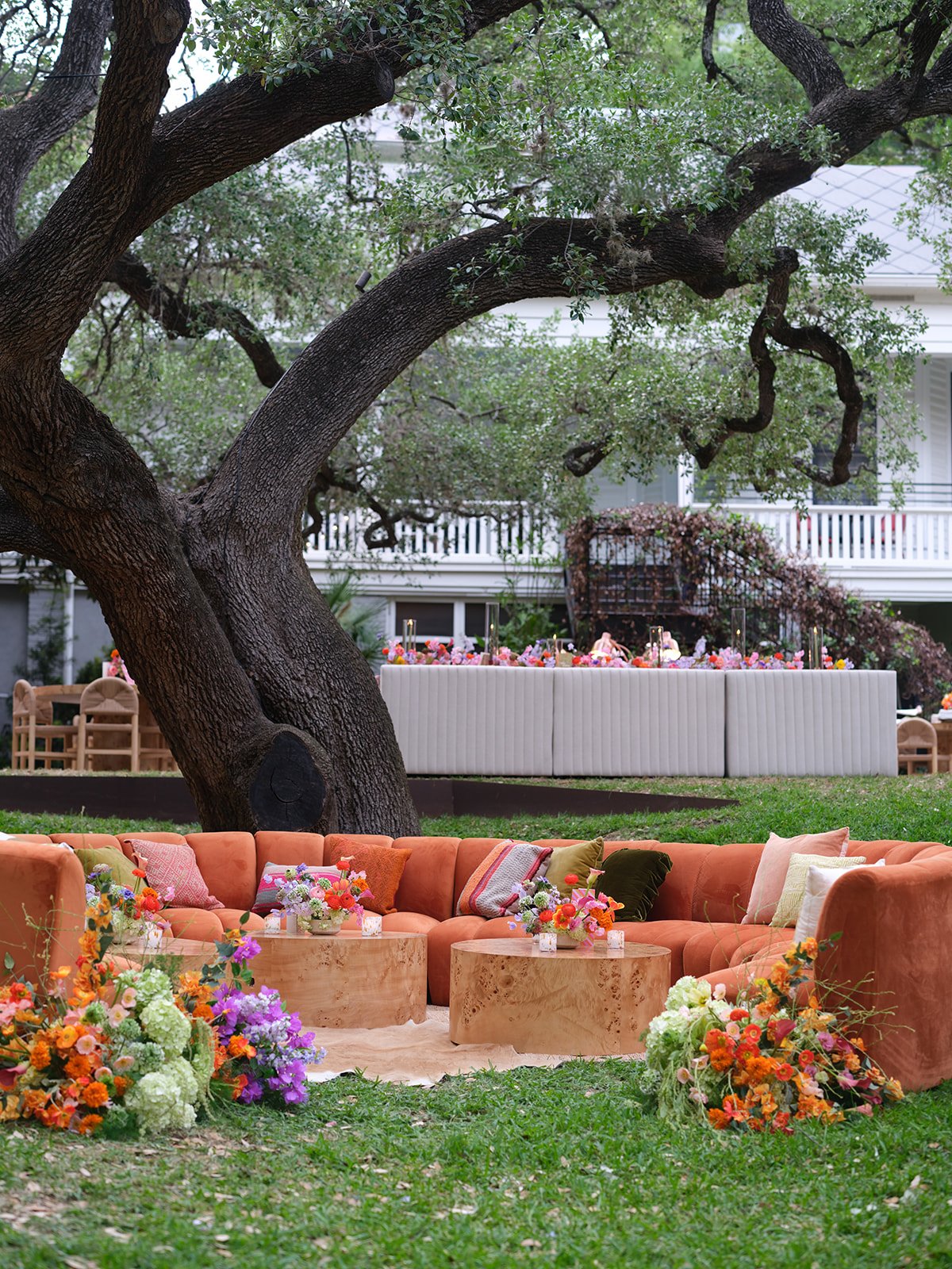  Rust velvet sectional lounge under an oak tree with floral centerpieces at a Hotel St. Cecilia wedding reception 