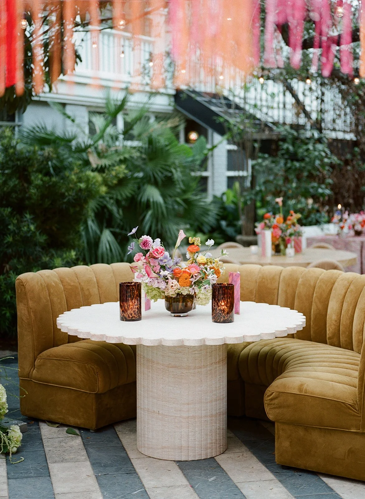  Mustard velvet curved booth seating around a round pedestal table with candlelight and florals at Hotel St. Cecilia 