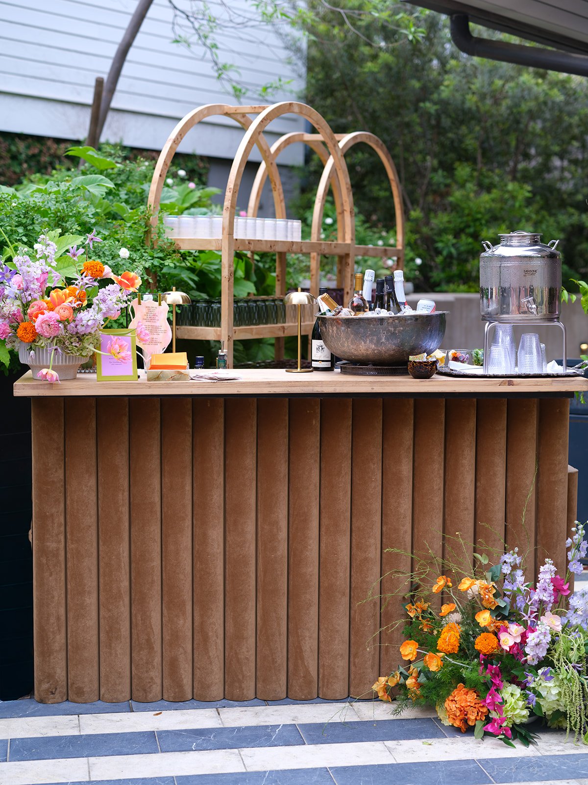  Arched wooden bar cart with glassware and a colorful floral arrangement at the base, Hotel St. Cecilia reception 