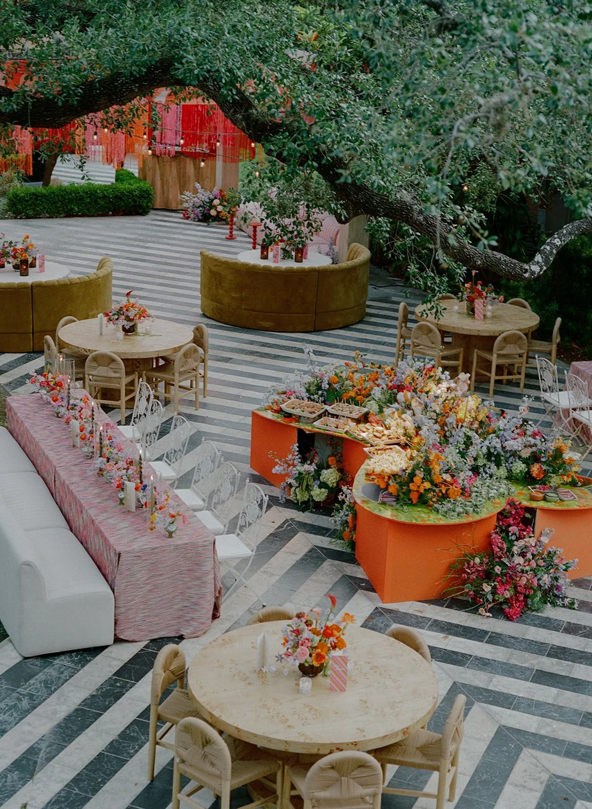  Wide view of the Hotel St. Cecilia reception lounge with striped flooring, curved banquettes, and cascading floral installations 