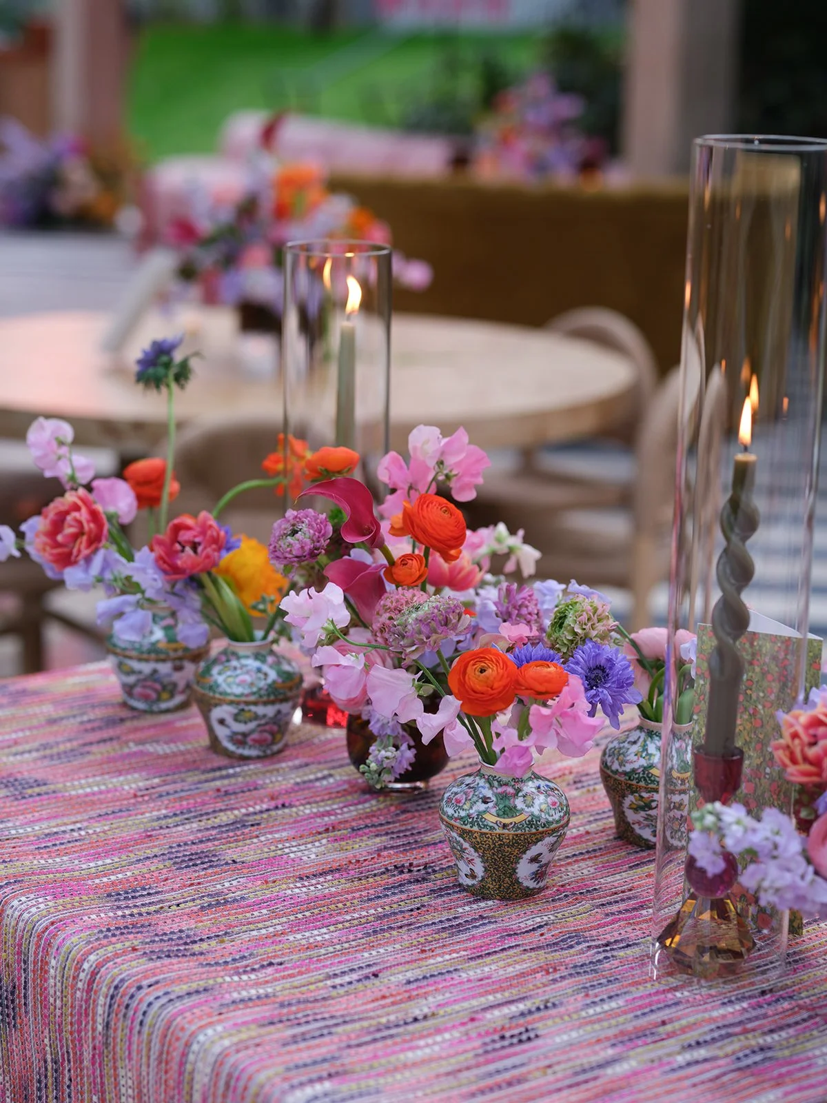  Close-up tablescape with antique vases of jewel-toned florals along a striped tablecloth at Hotel St. Cecilia 