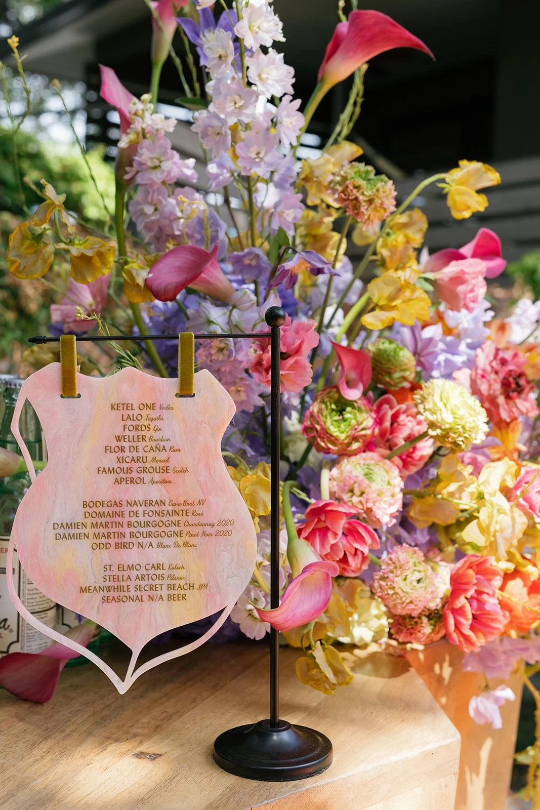  Floral-framed menu card on a stand beside a lush purple, pink, and yellow floral arrangement at Hotel St. Cecilia   