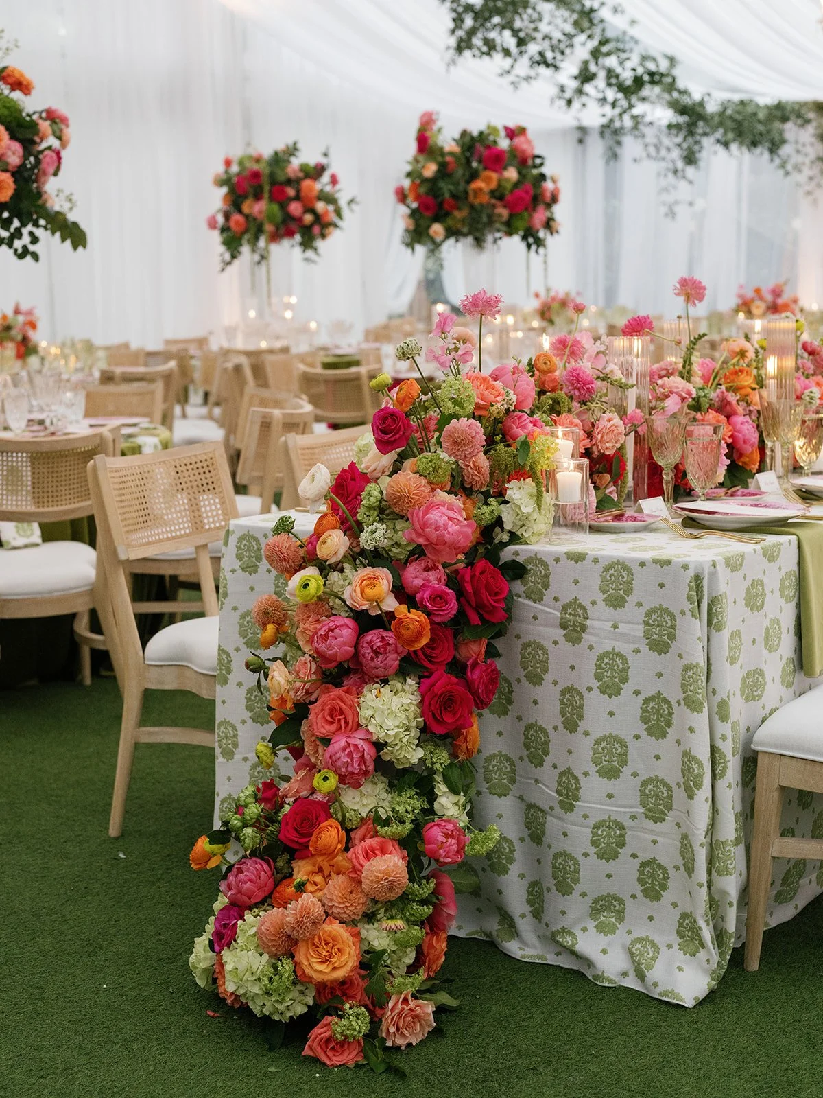  Long feasting table with a dramatic cascading floral runner in red, pink, and cream spilling off the end onto the lawn at Woodbine Mansion 