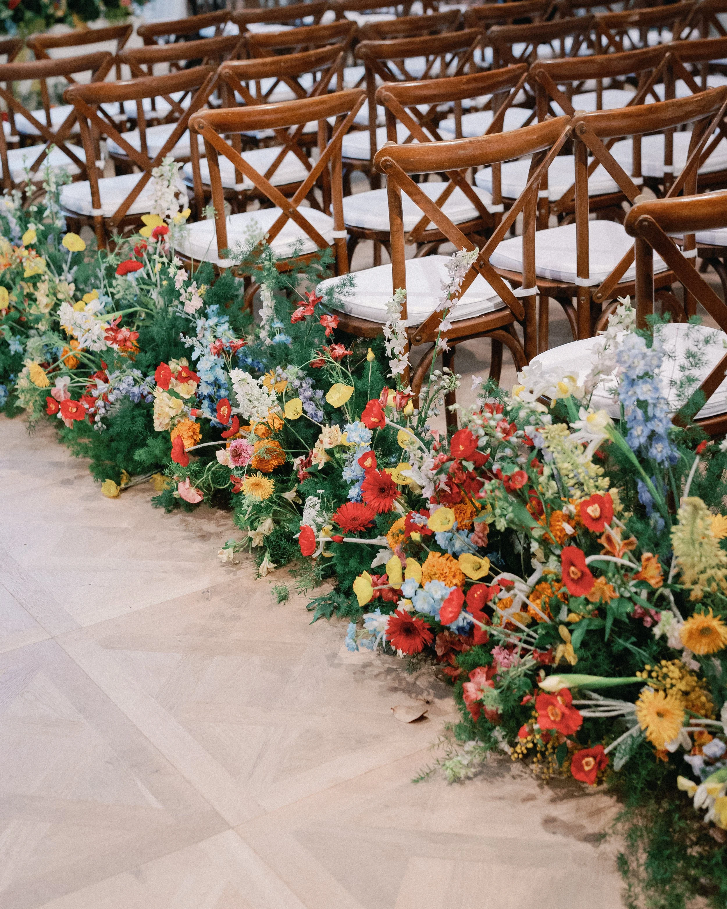  Close-up of the aisle floral design in red, orange, yellow, and blue along the cross-back ceremony chairs at Mattie's 