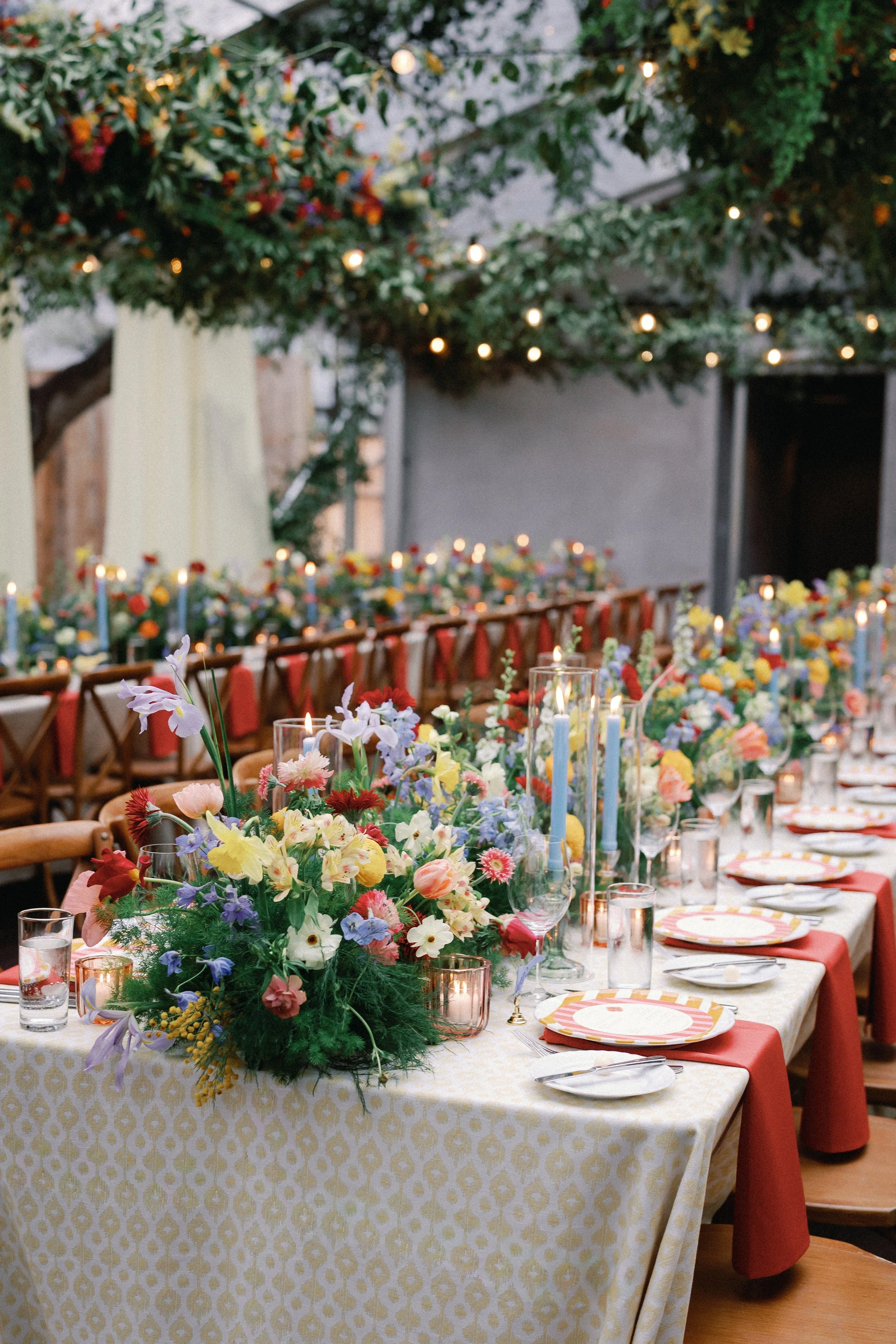  Long reception table with a checkered patterned linen, red napkins, and colorful floral centerpieces at Mattie's 