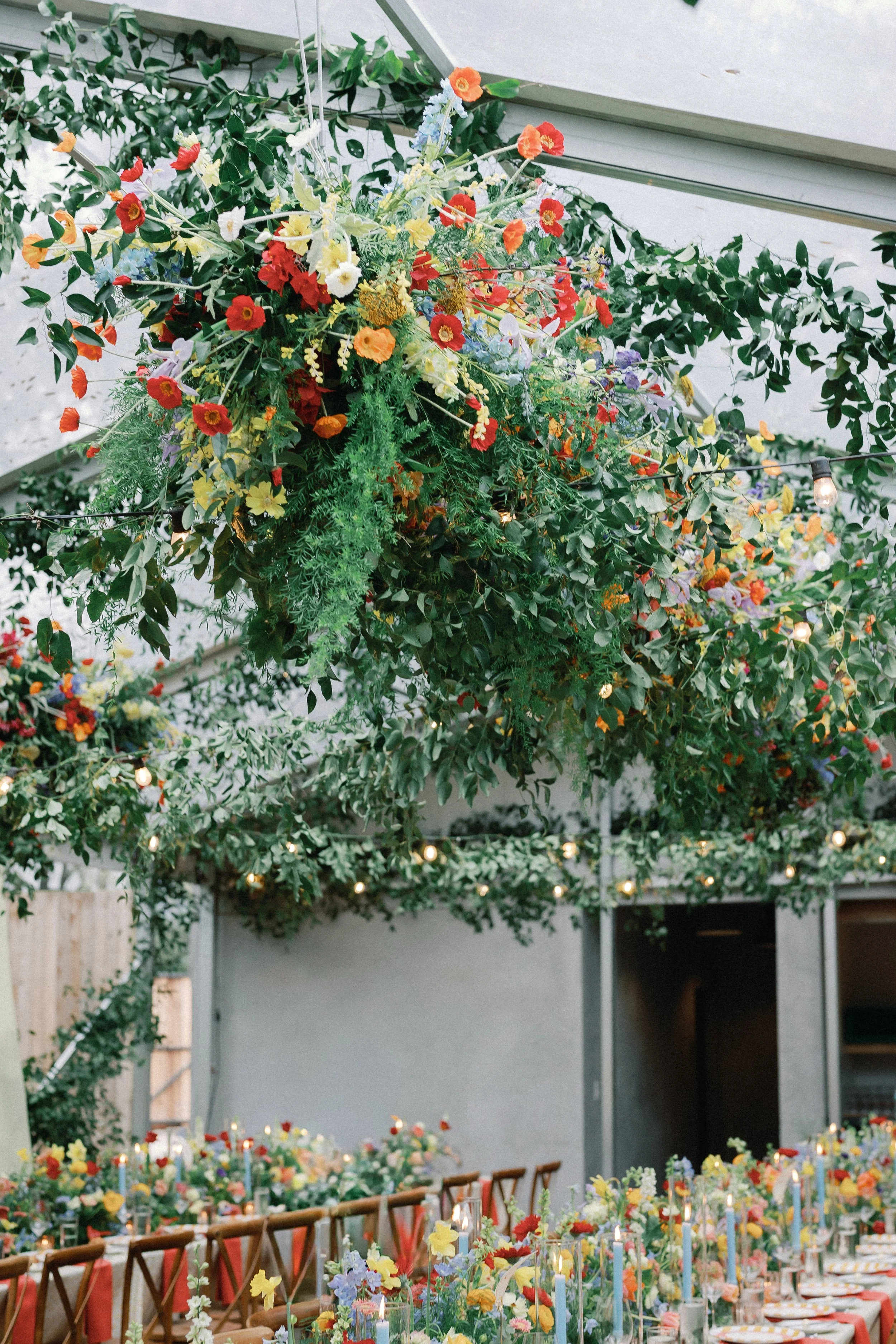  Tall hanging floral and greenery installation against the building facade with reception tables below at Mattie's 
