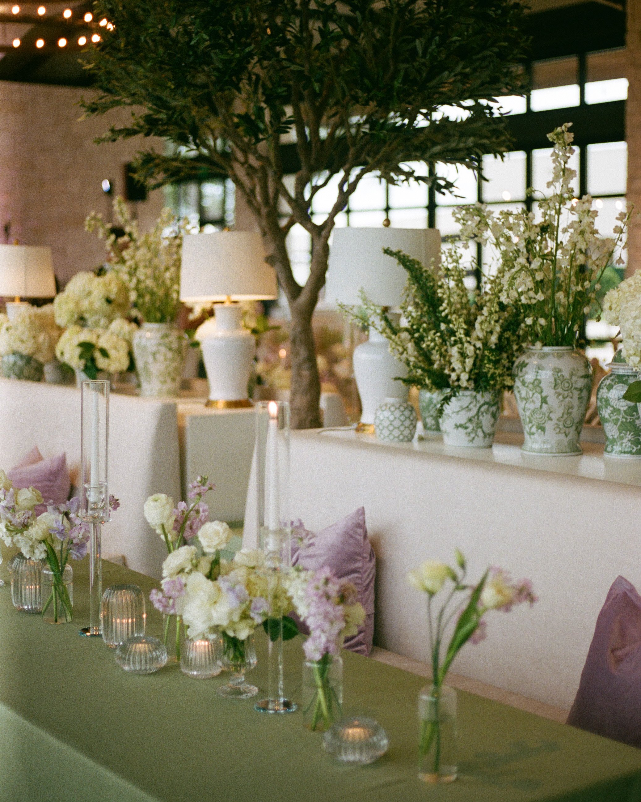  Long feasting table at Omni Barton Creek wedding reception with sage green linen, lavender pillows, faux olive trees, and taper candles 