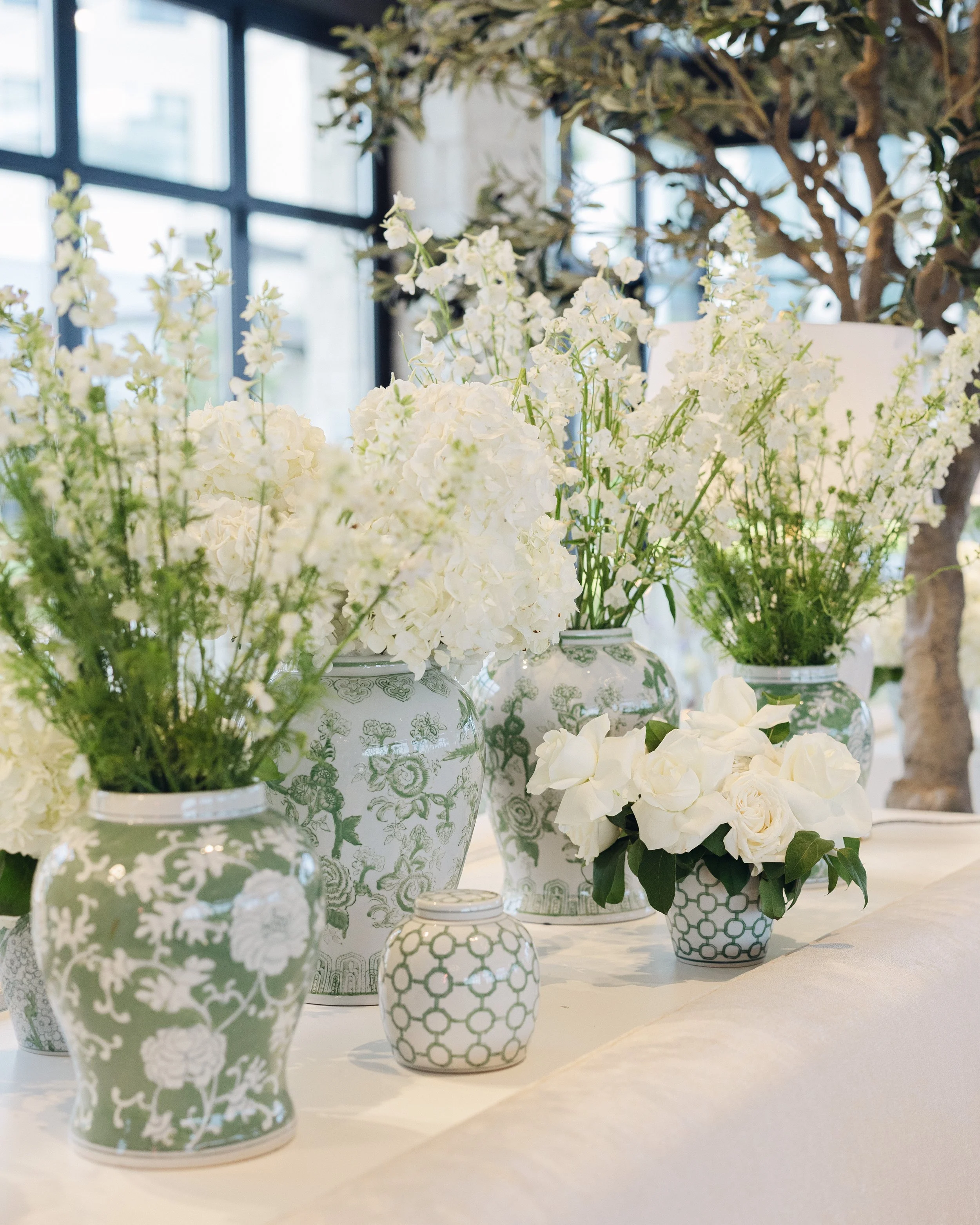  Green and white chinoiserie ginger jars filled with white hydrangea and delphinium on reception table 