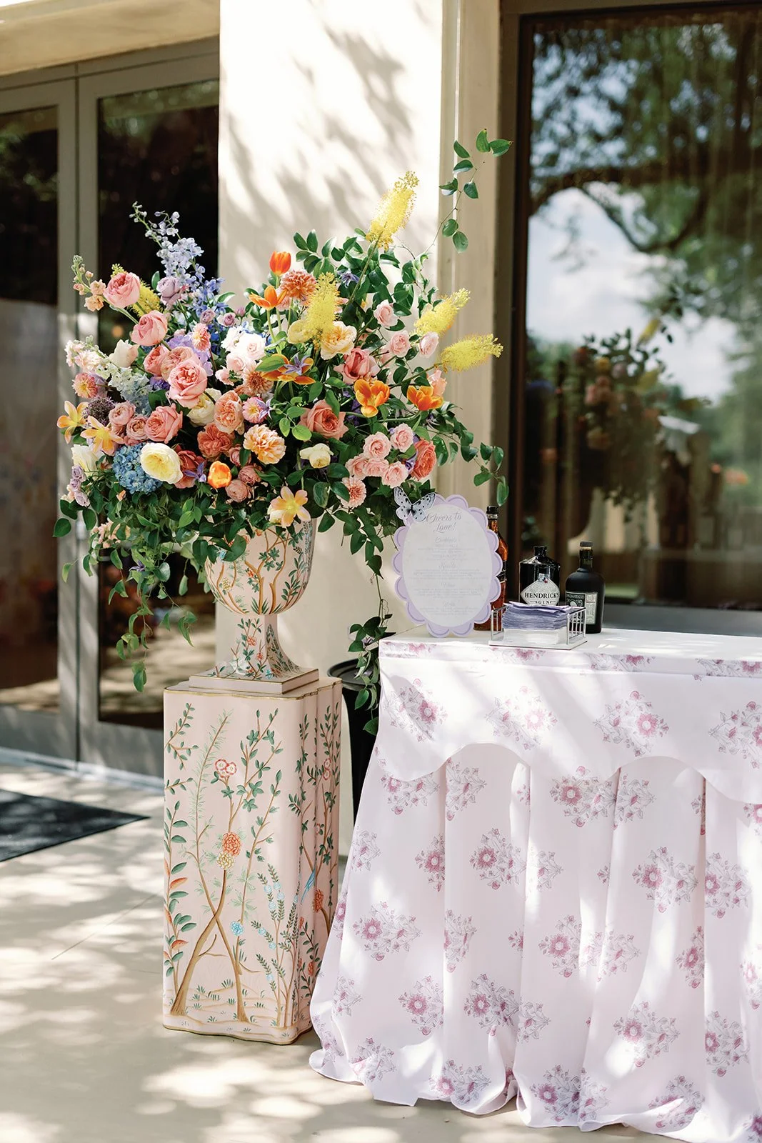  Tall floral arrangement in peach, coral, and lavender on a floral patterned pedestal near glass doors at Four Seasons Austin 