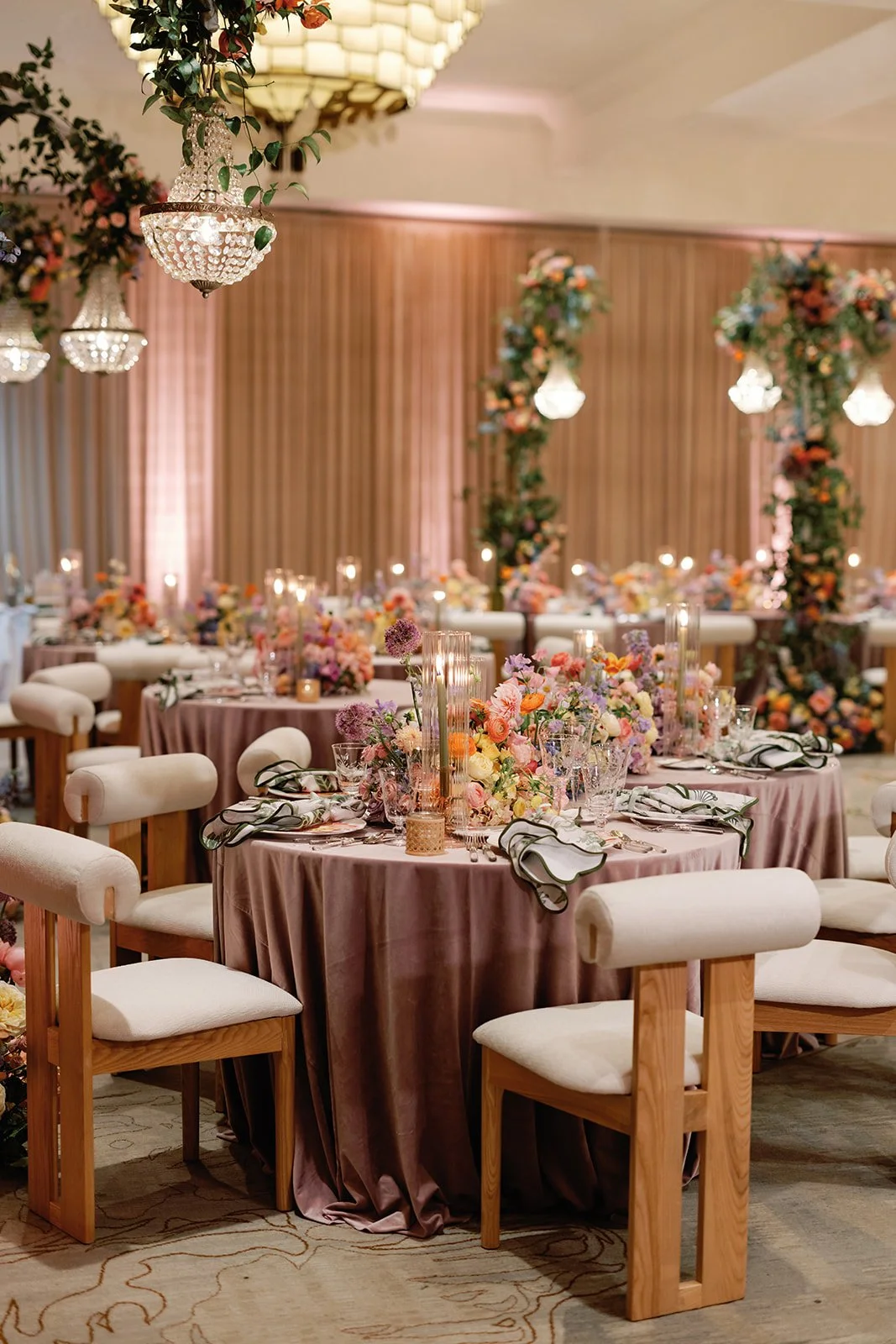  Wide view of Four Seasons Austin reception room with blush drapery, crystal chandeliers, and floral arches over round tables 