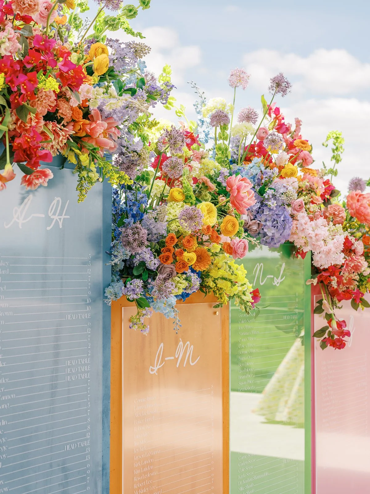  Colorful floral arrangement with seating chart on colorful glass panels and a blue sky at The Videre Estate   