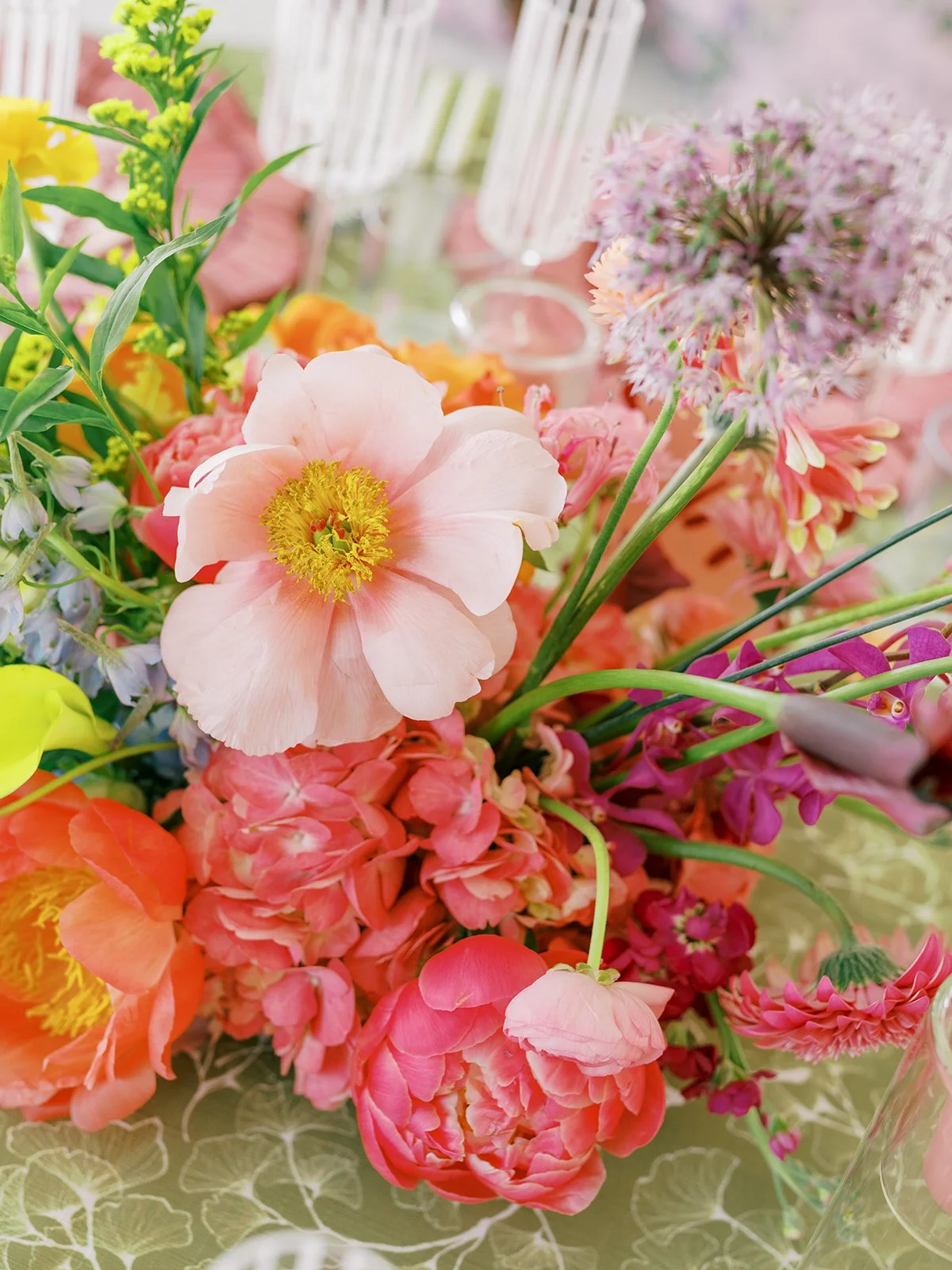  Close up centerpiece with peach ranunculus, pink hydrangea, and coral blooms on green patterned linen 