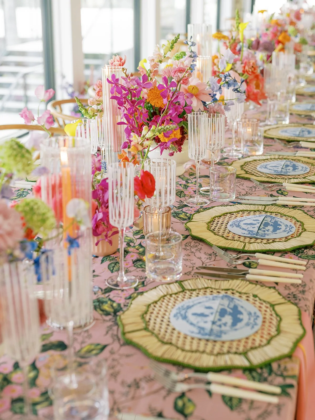  Long reception table lined with pink flower shaped chargers and a colorful centerpiece 
