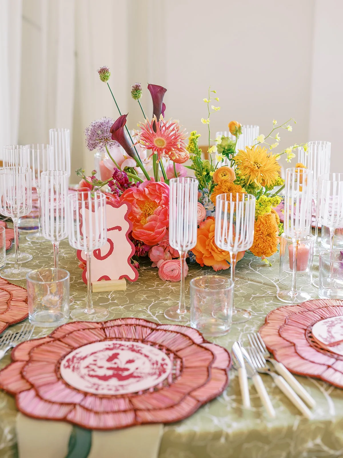  Table setting with pink flower shaped charger, colorful centerpiece, and table number 