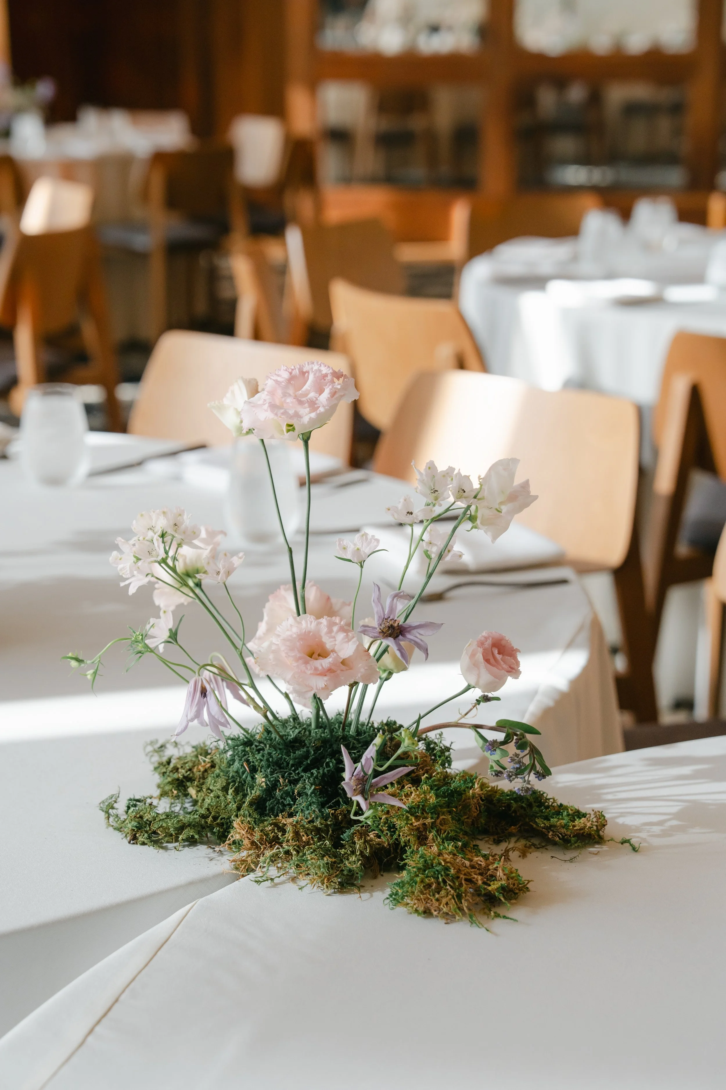  Close-up of a loose centerpiece of blush lisianthus and sweet peas rising from moss at an Austin Proper Hotel sangeet 