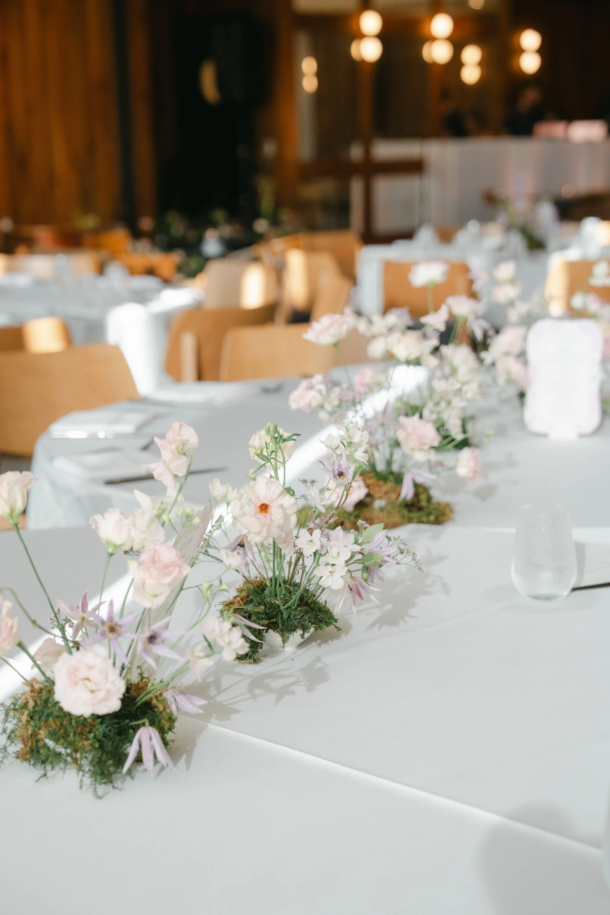  A row of small moss and blush floral arrangements down a long reception table at Austin Proper Hotel 