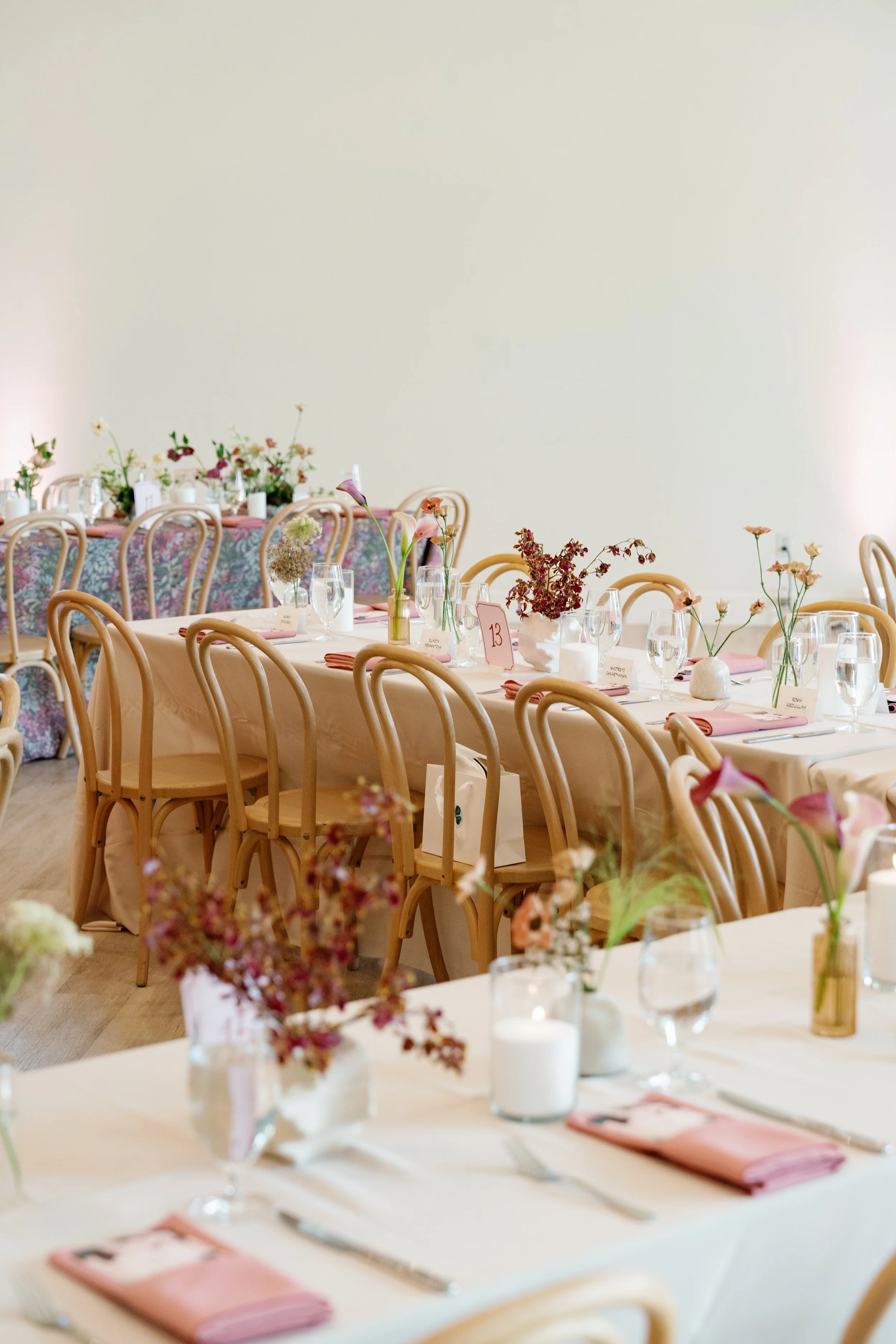  Bud vases of blush, white and burgundy blooms with candles on a reception table at The Arlo in Austin 