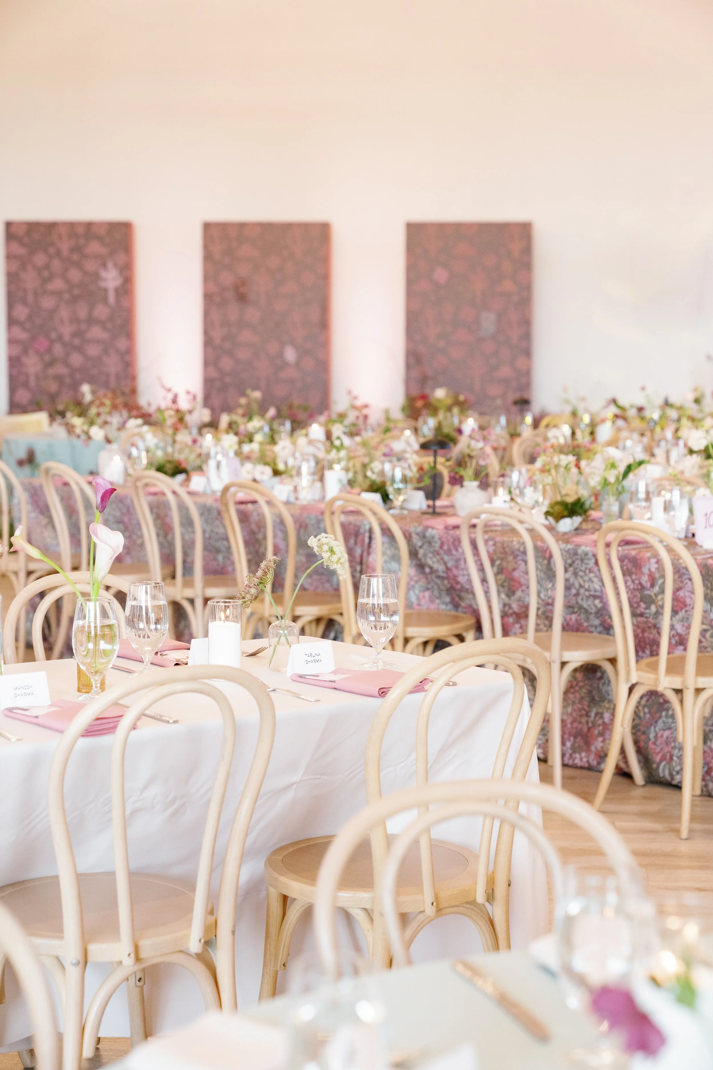  Low greenery and floral arrangement beneath three patterned panels behind the head table at The Arlo 