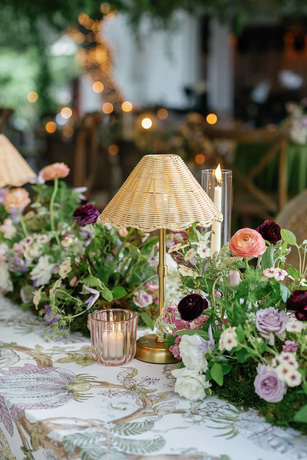  Long reception tables with botanical-print linens and low garden arrangements under a greenery ceiling at The Allan House 
