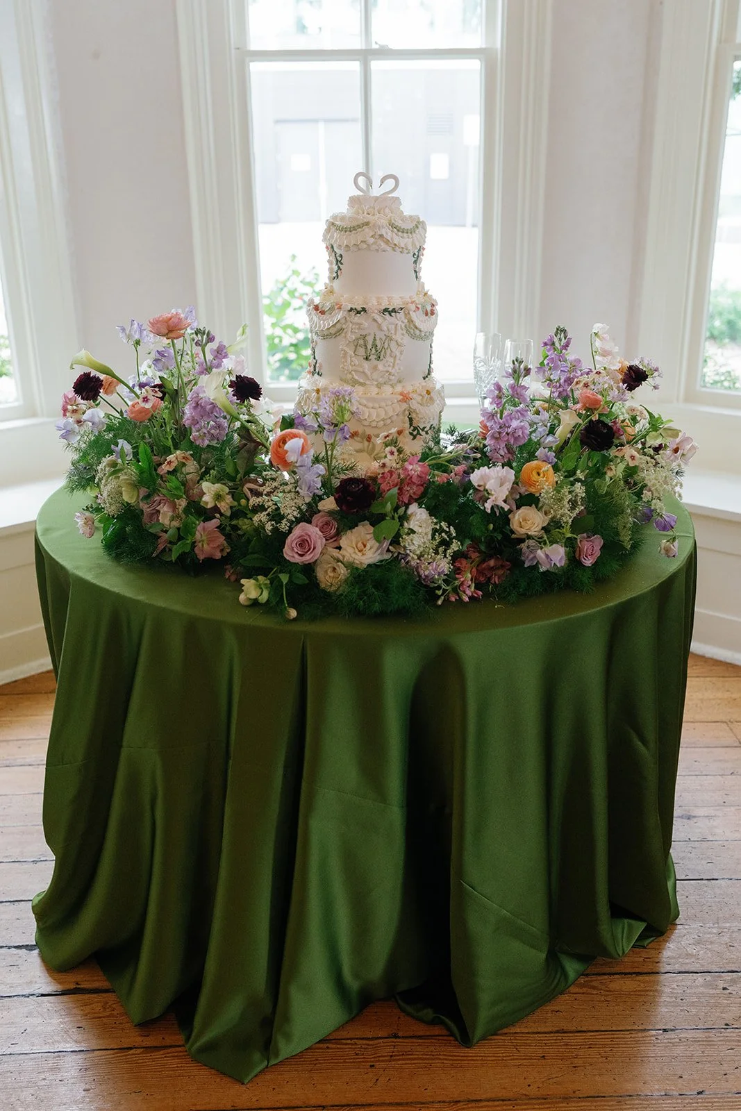  Wedding cake on an olive velvet table surrounded by a ring of colorful blooms at The Allan House 