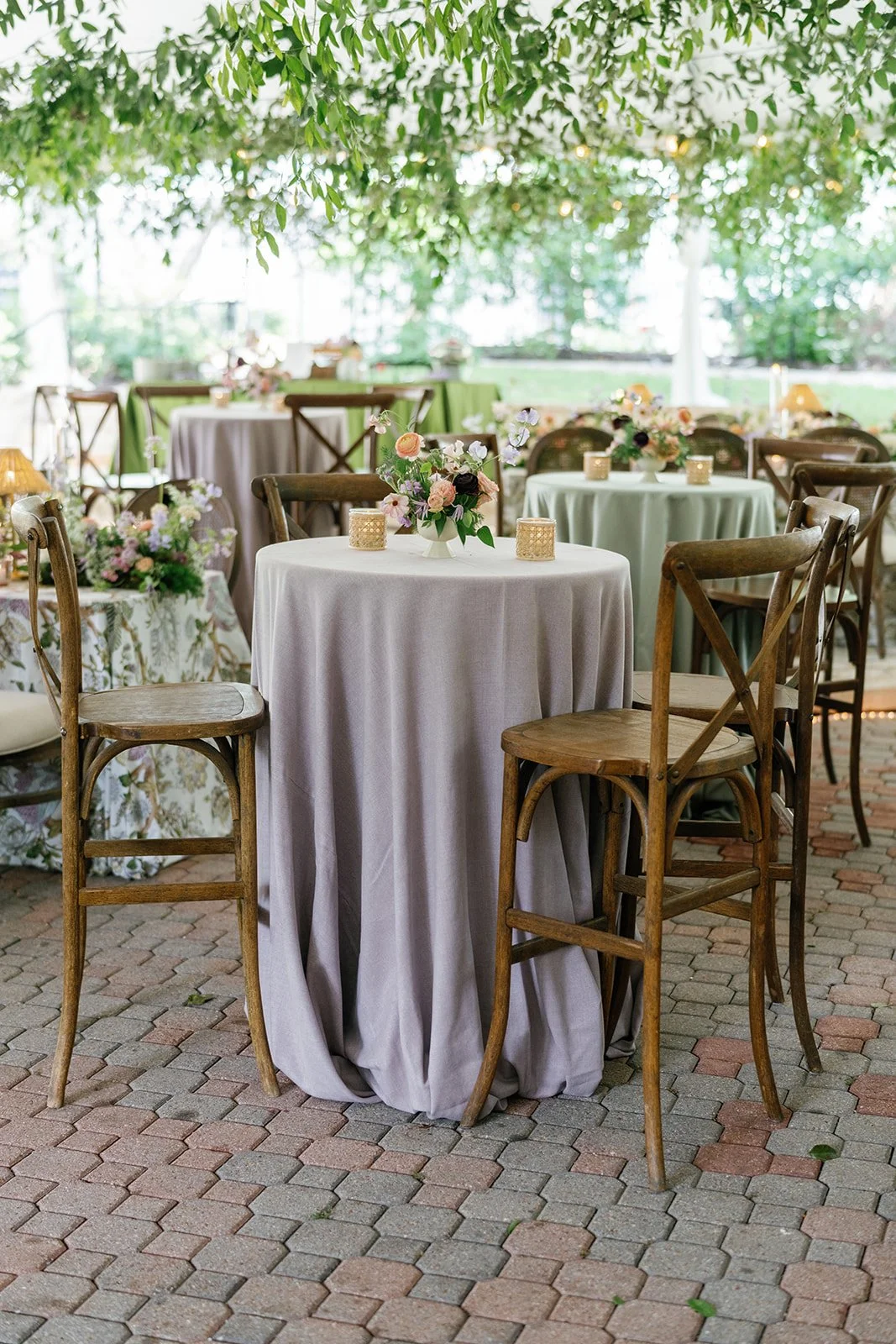 Round reception tables in lilac and sage linens with small floral arrangements under the tent at The Allan House 