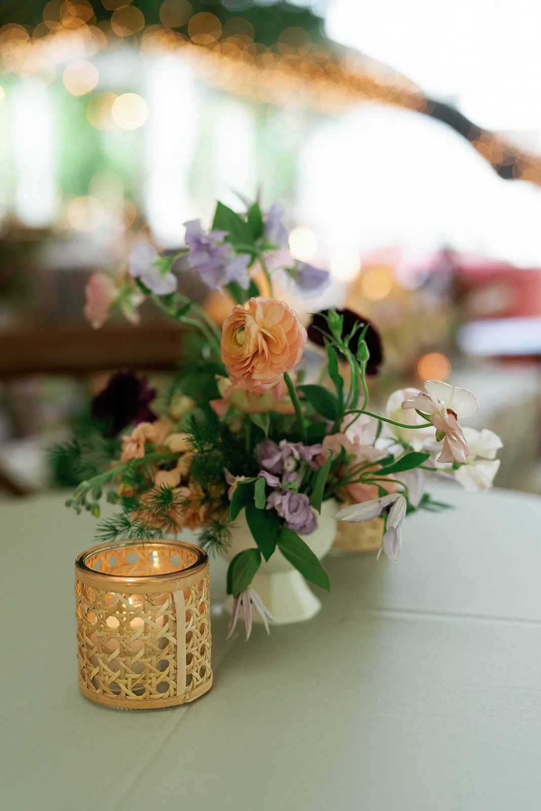  Close-up of garden roses, ranunculus and greenery on a botanical-print linen at a wedding at The Allan House 