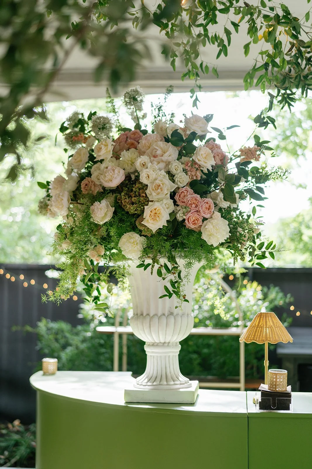  Footed urn of blush and white garden roses on a green bar at a tented reception at The Allan House 