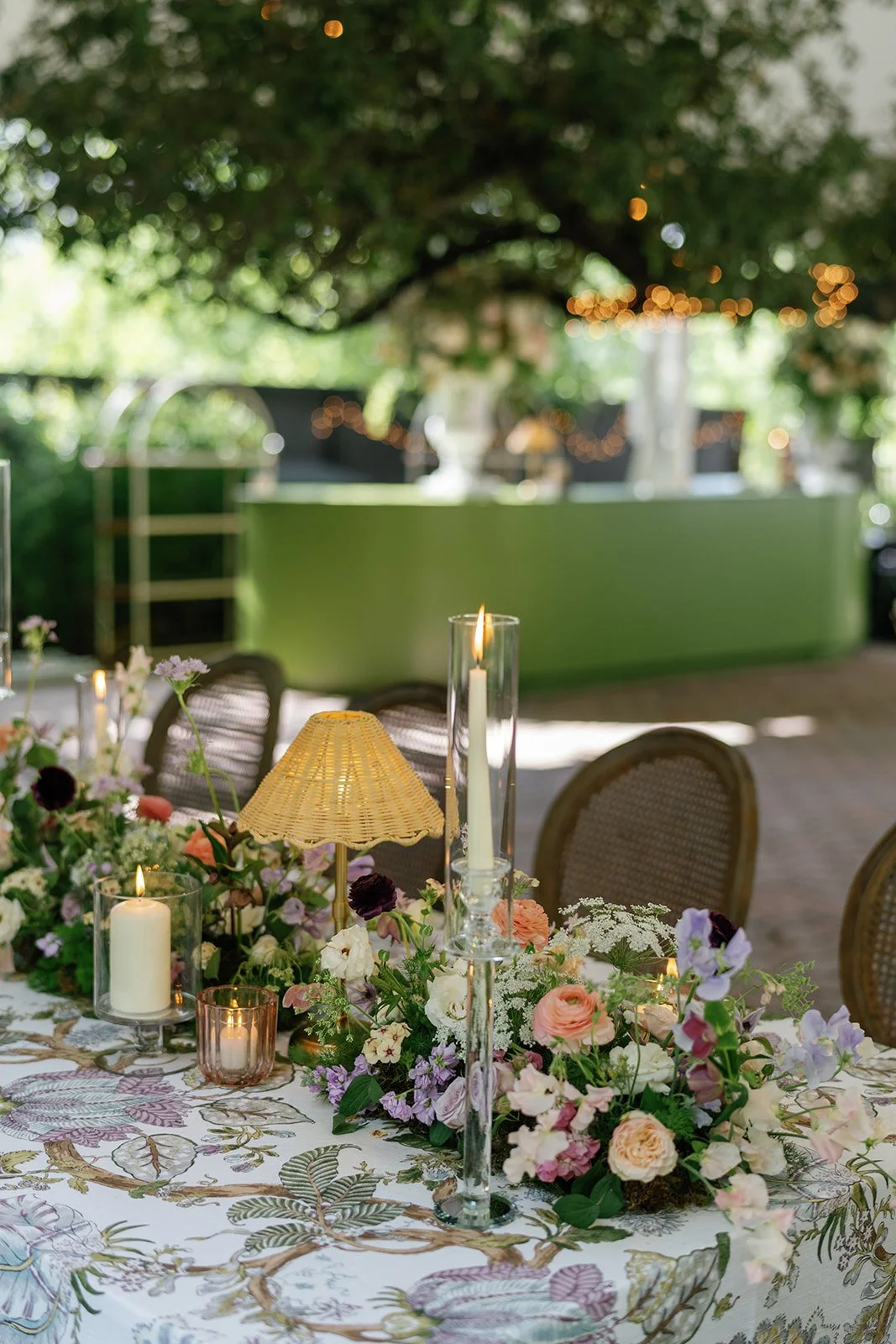  Rattan lamps, candles and lush garden florals running down a long reception table at The Allan House 