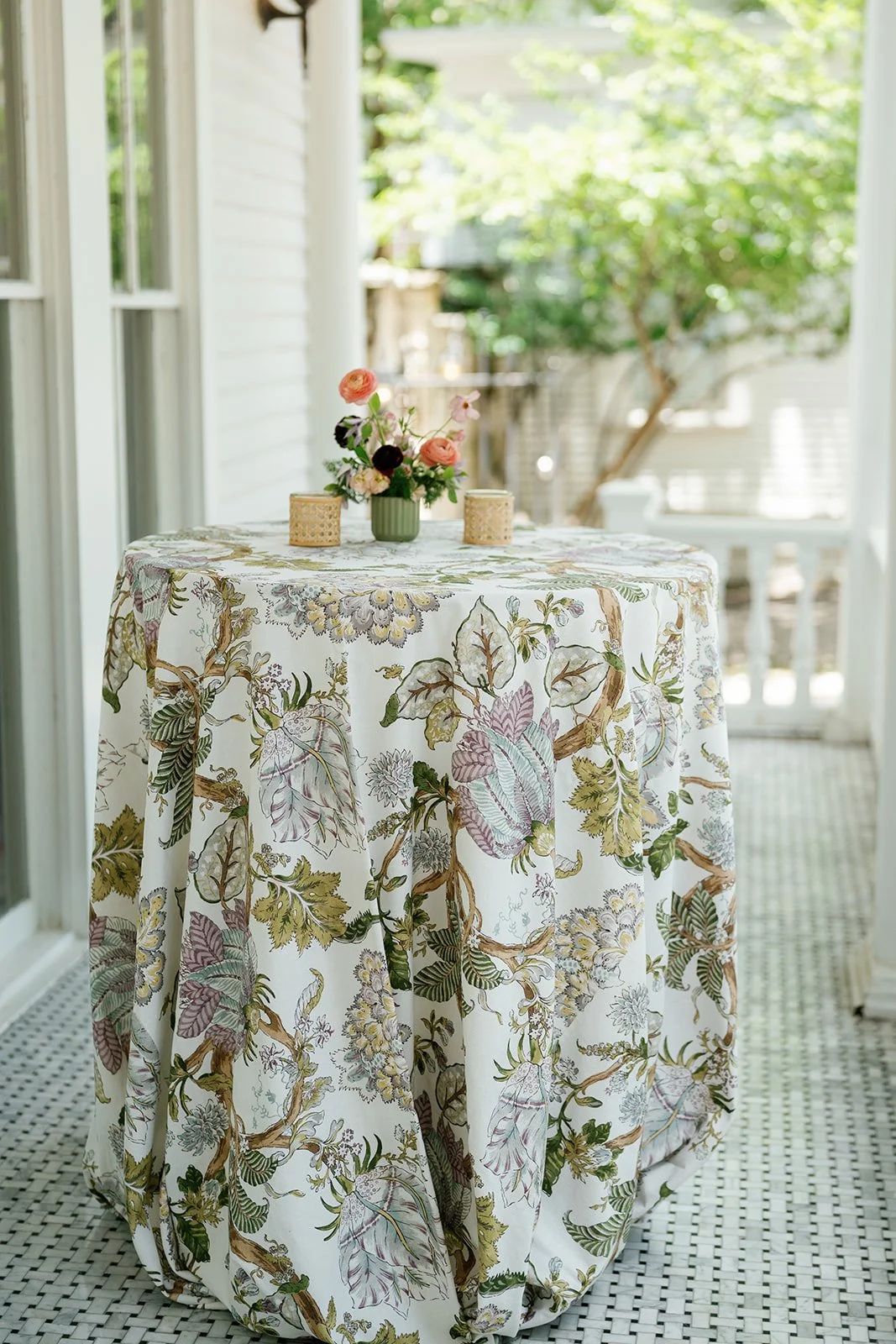  Veranda cocktail table with a botanical linen and a small bud vase arrangement at The Allan House 