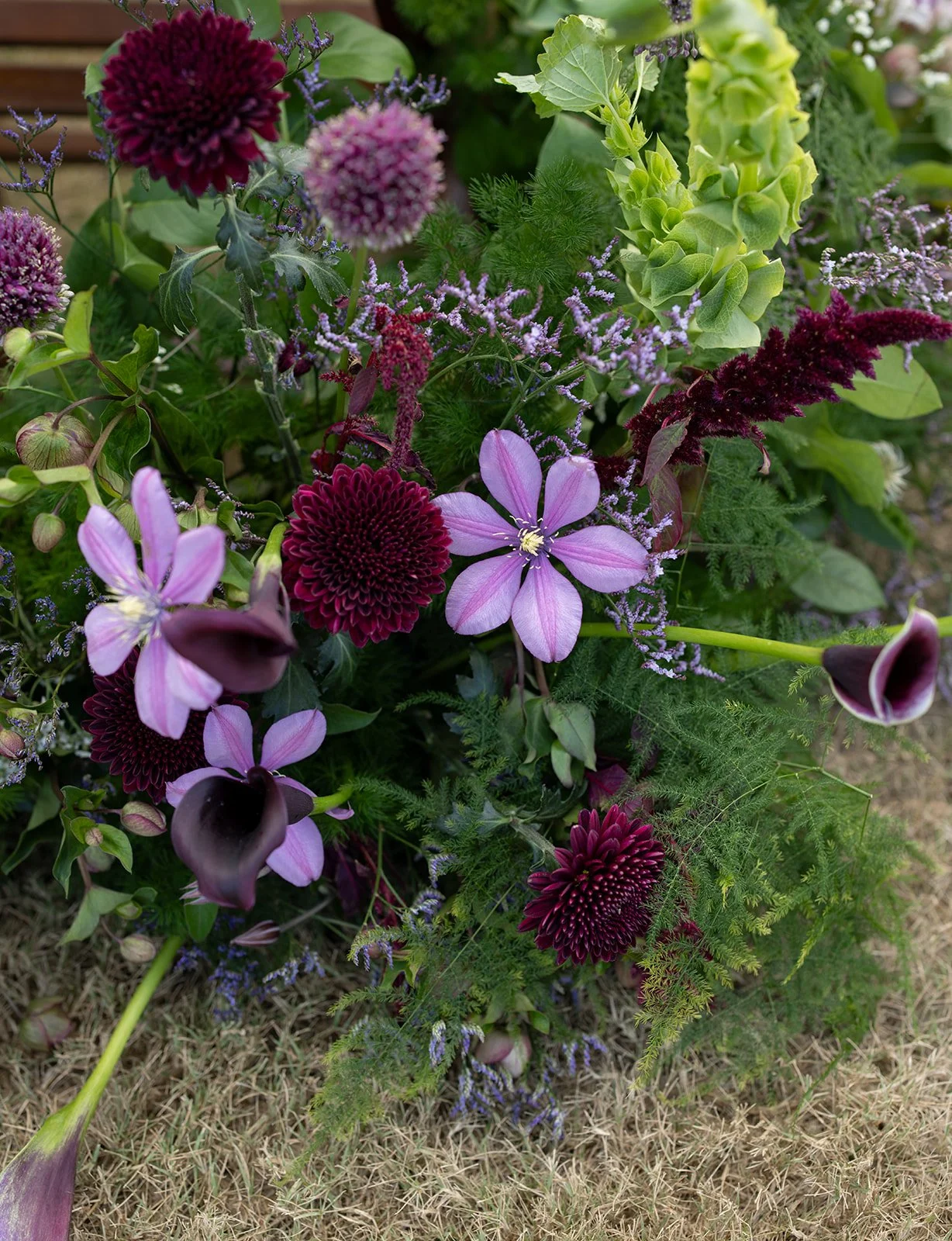  Close-up of burgundy dahlias, purple clematis and plum calla lilies from a Camp Lucy wedding ceremony 