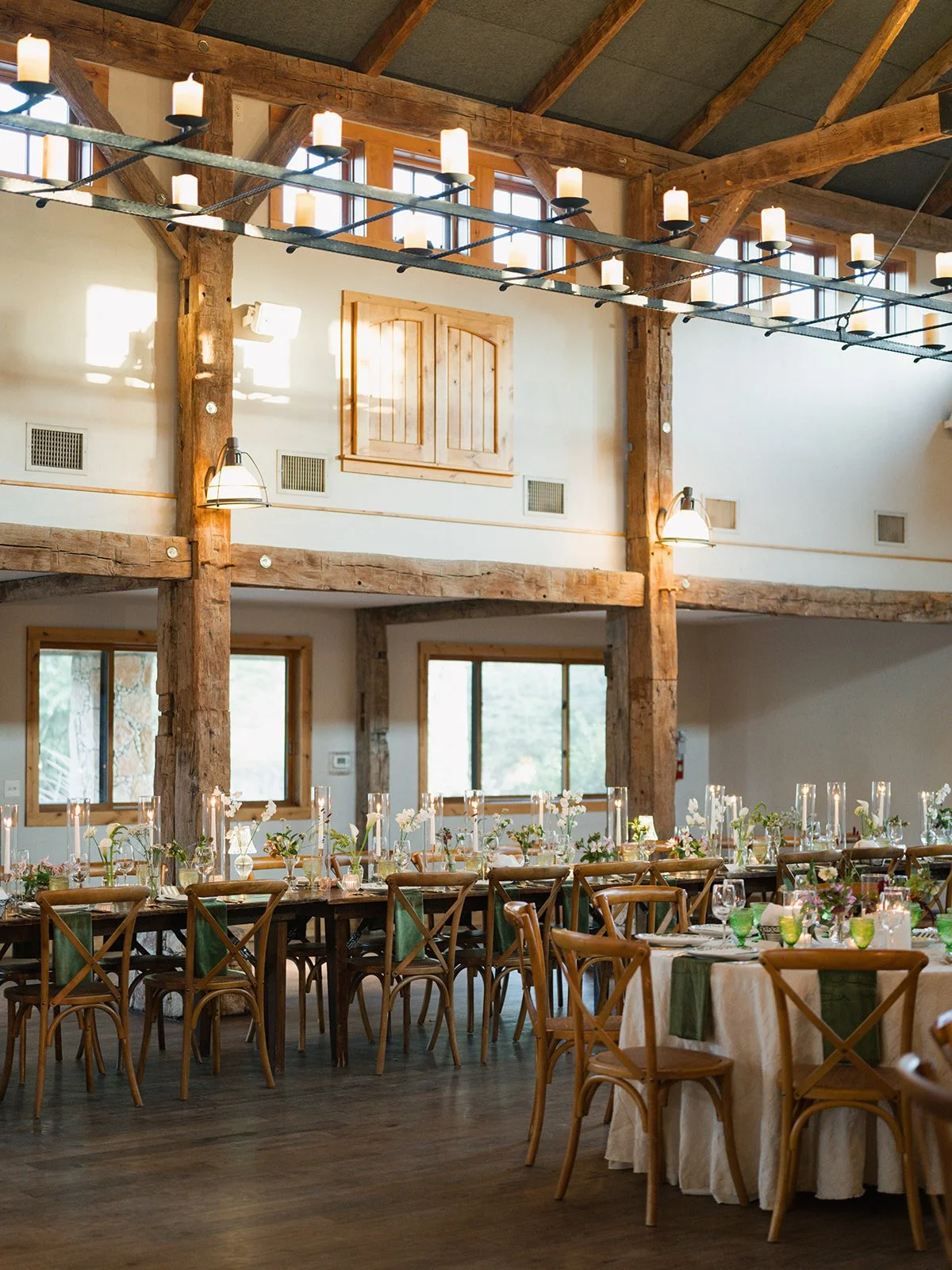  Candlelit wedding reception at Camp Lucy with long farm tables and round tables beneath timber beams and candle chandeliers 