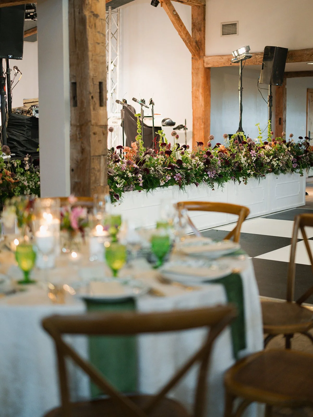  Lush floral garland of burgundy, mauve and apricot blooms along the band stage beside a checkered dance floor at Camp Lucy 